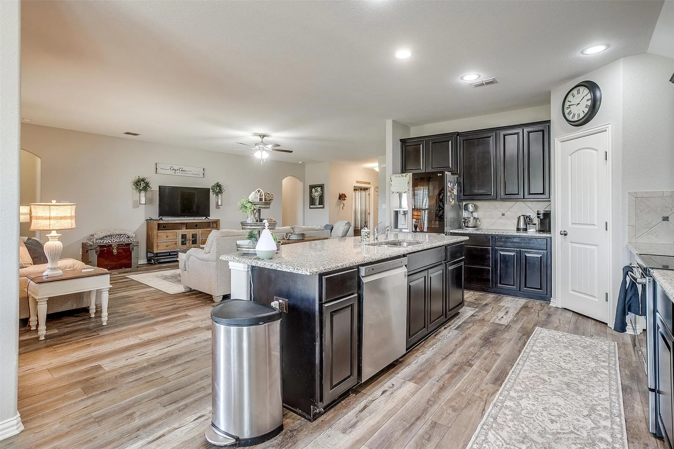 Kitchen featuring arched walkways, decorative backsplash, open floor plan, light wood-type flooring, and ceiling fan