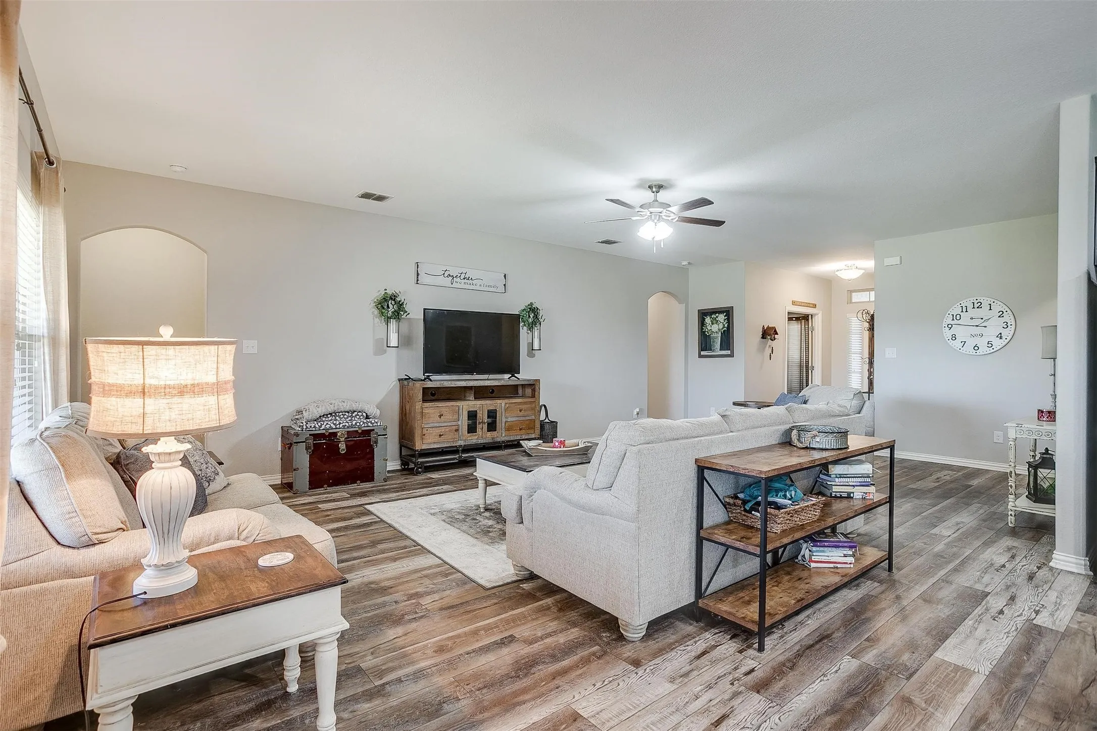 Living room featuring arched walkways, wood finished floors, and ceiling fan