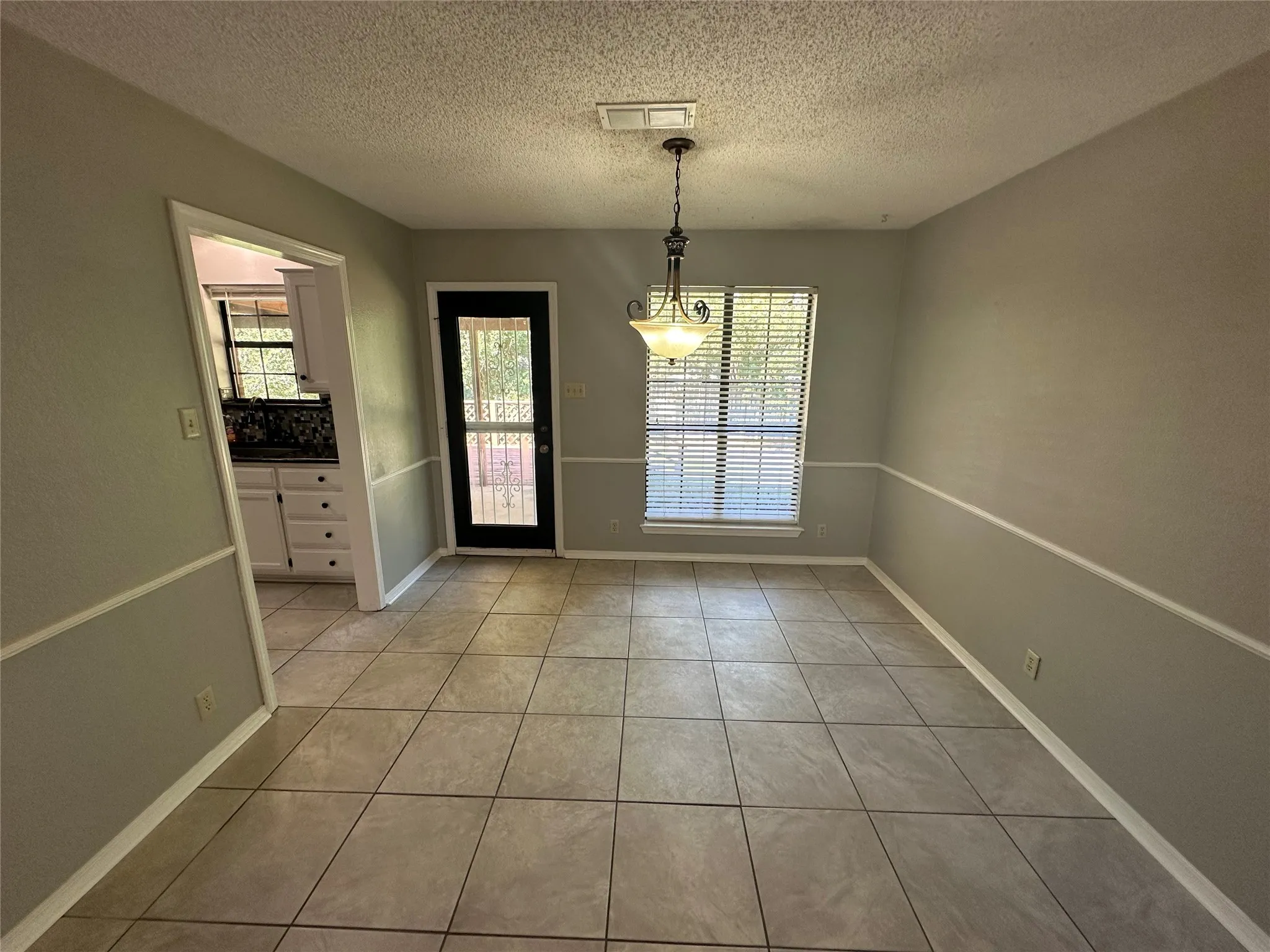 Unfurnished dining area with light tile patterned flooring and a textured ceiling