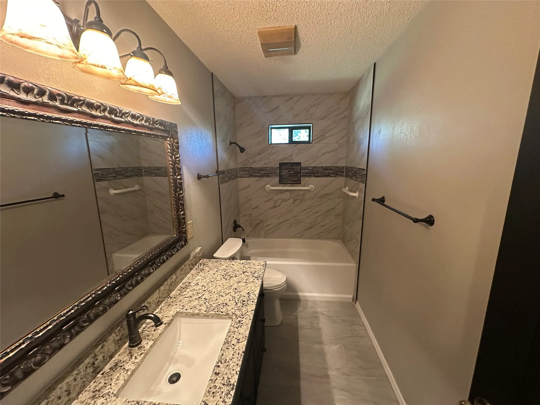 Full bath featuring vanity, a textured ceiling, and  shower combination