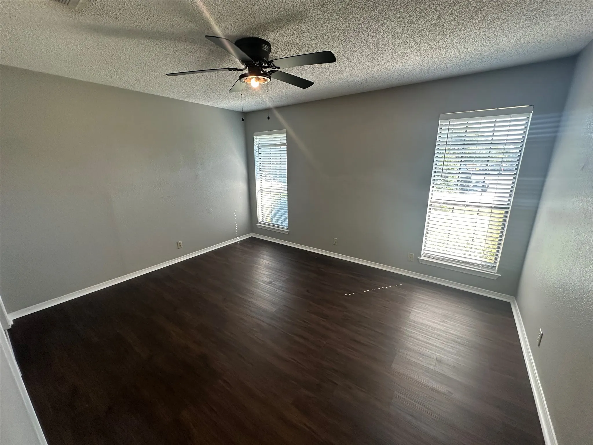 Spare room featuring a textured ceiling, dark wood-style flooring, and ceiling fan