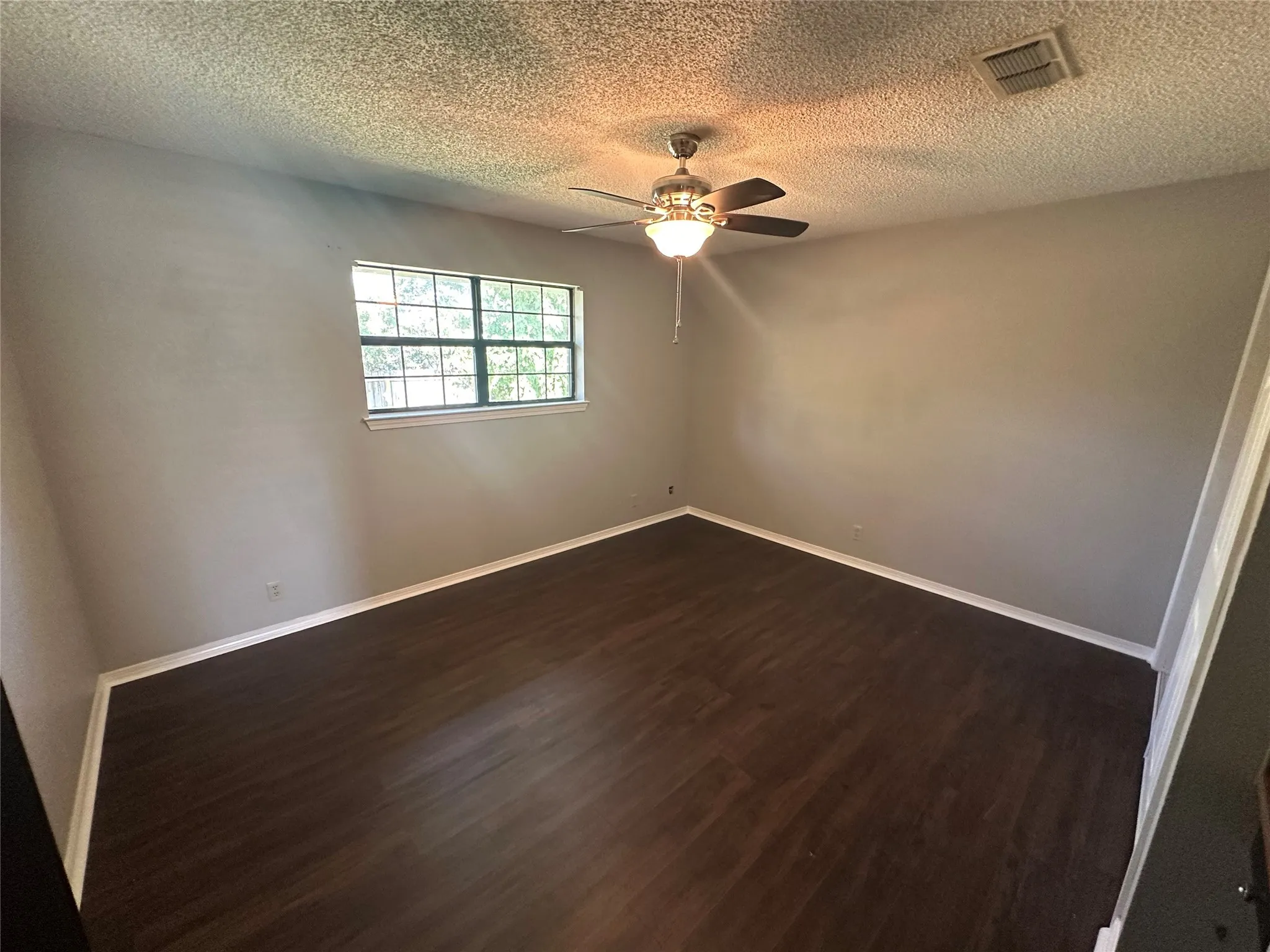 Spare room featuring dark wood finished floors, a textured ceiling, and ceiling fan