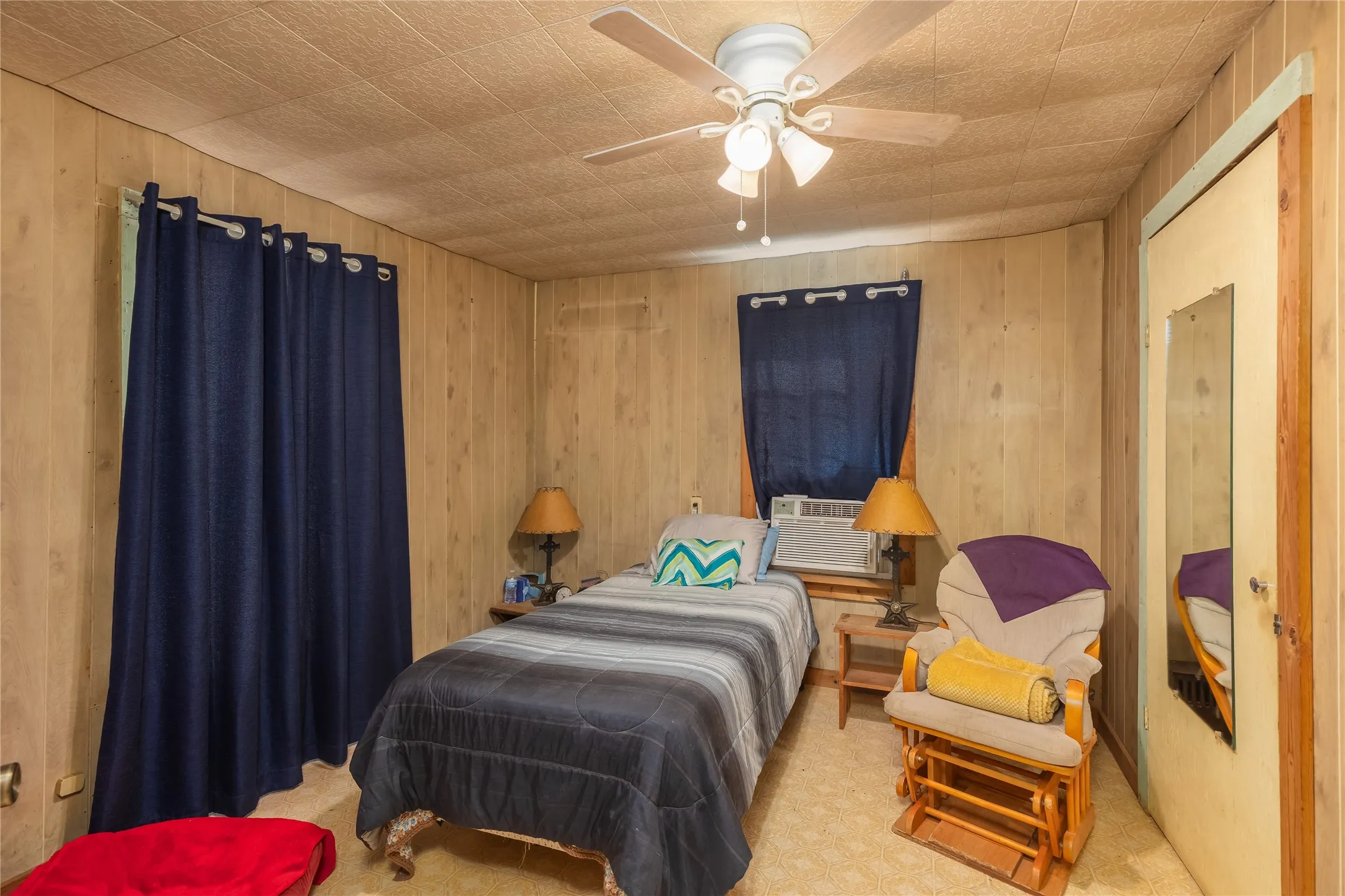 Bedroom featuring wood walls, a ceiling fan, and cooling unit