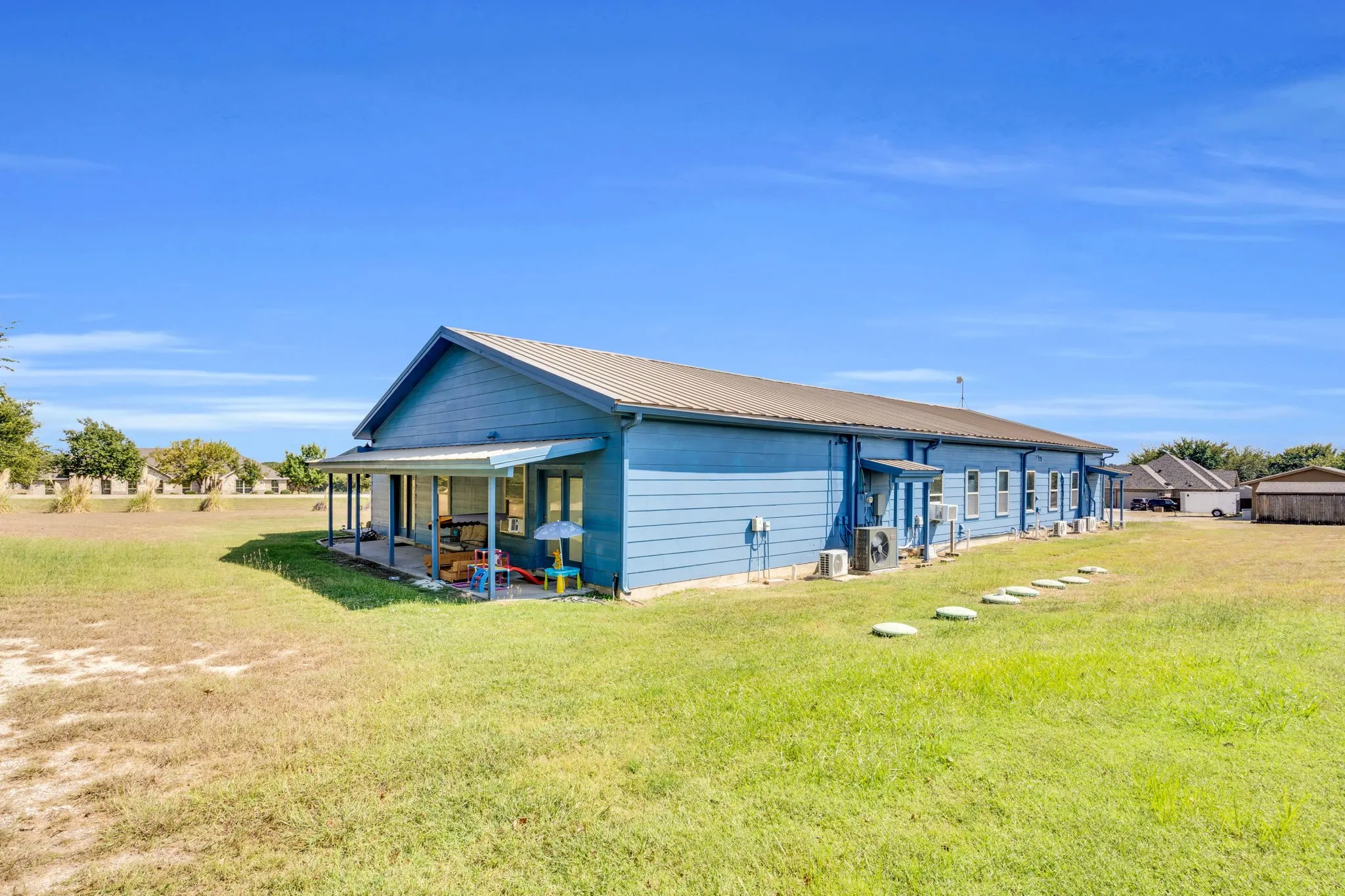 Back of house with a lawn, a patio area, and a metal roof