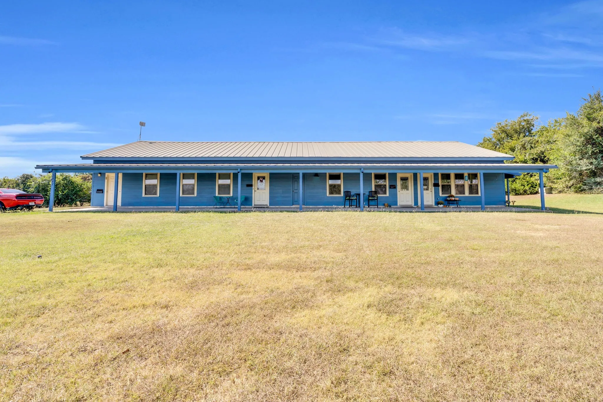 Country-style home featuring covered porch, a front lawn, and a metal roof