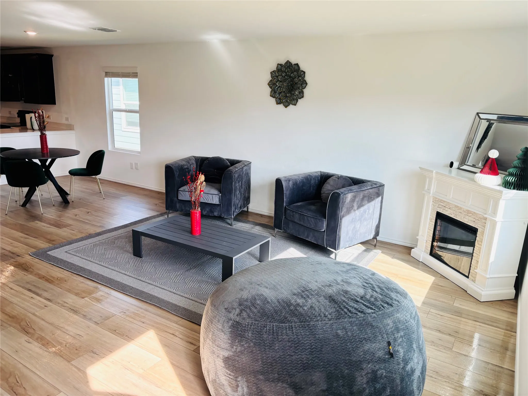 Living area with light wood-style flooring and a glass covered fireplace