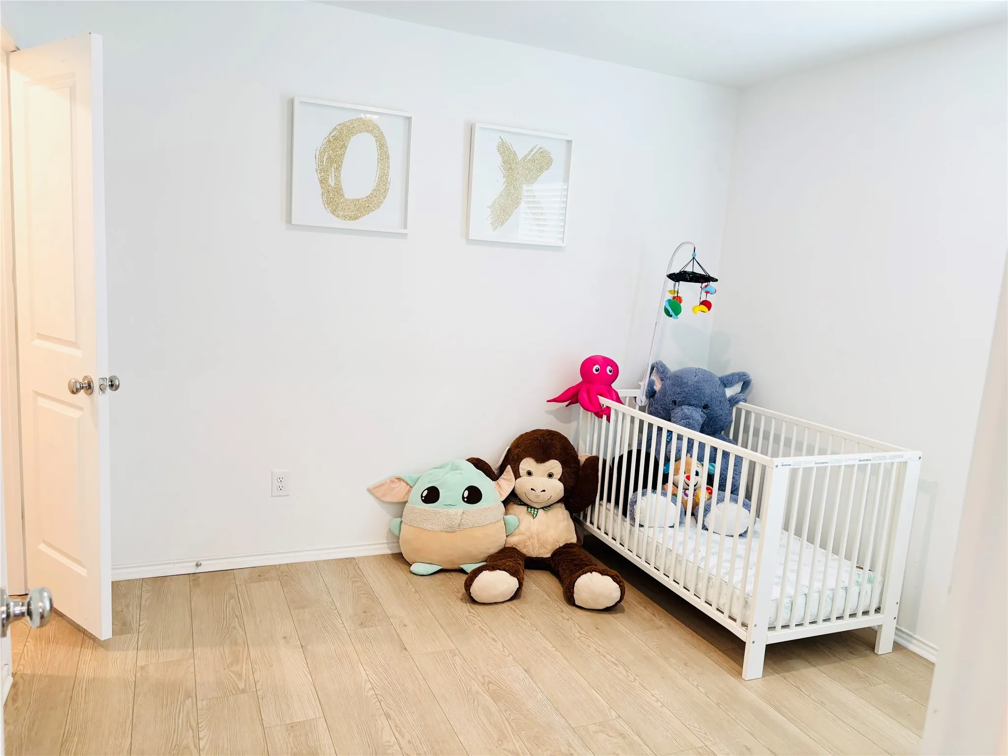 Bedroom with wood finished floors and a crib