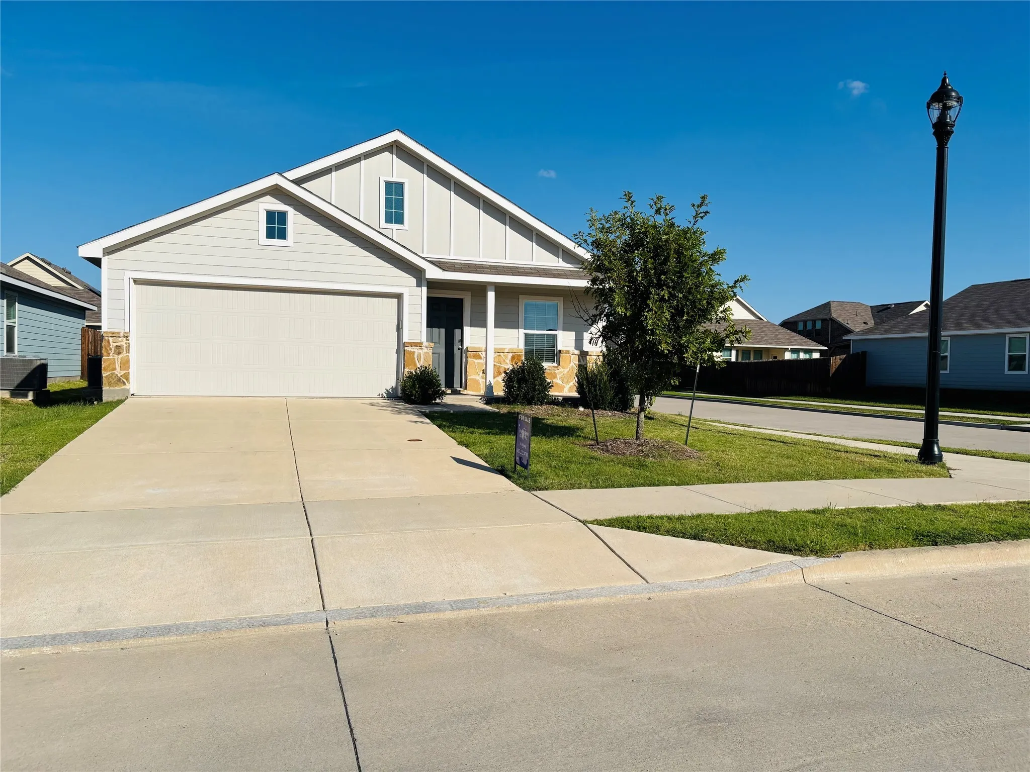 Craftsman inspired home featuring board and batten siding, driveway, and a front lawn