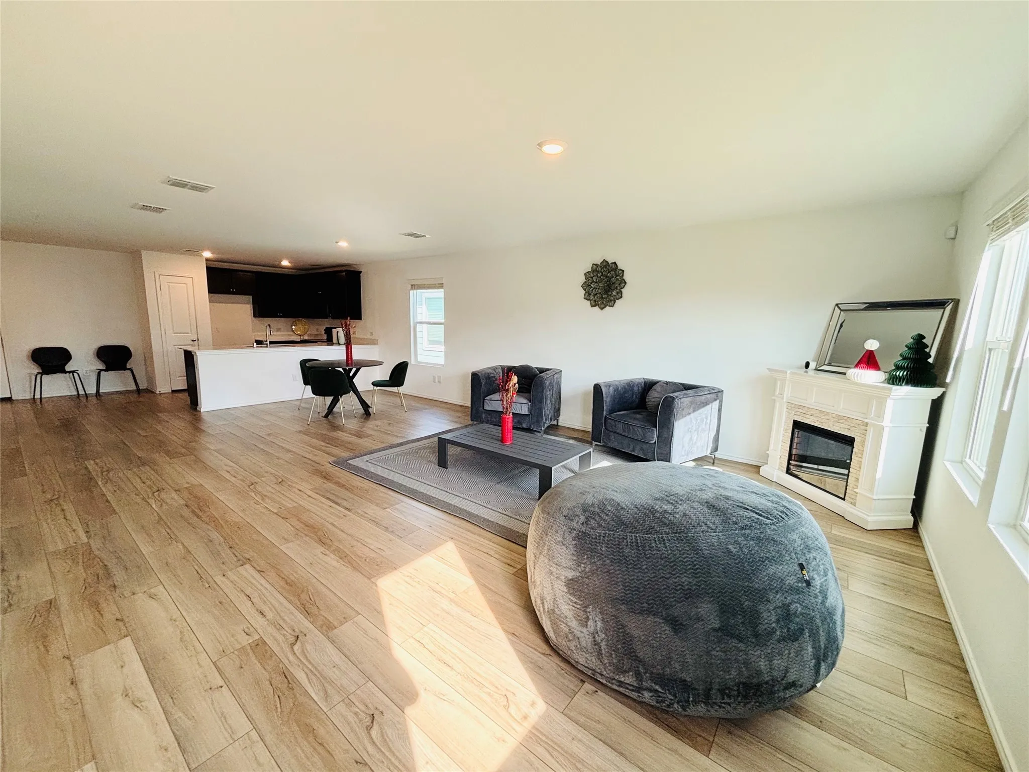 Living area with light wood-style floors, a glass covered fireplace, and recessed lighting