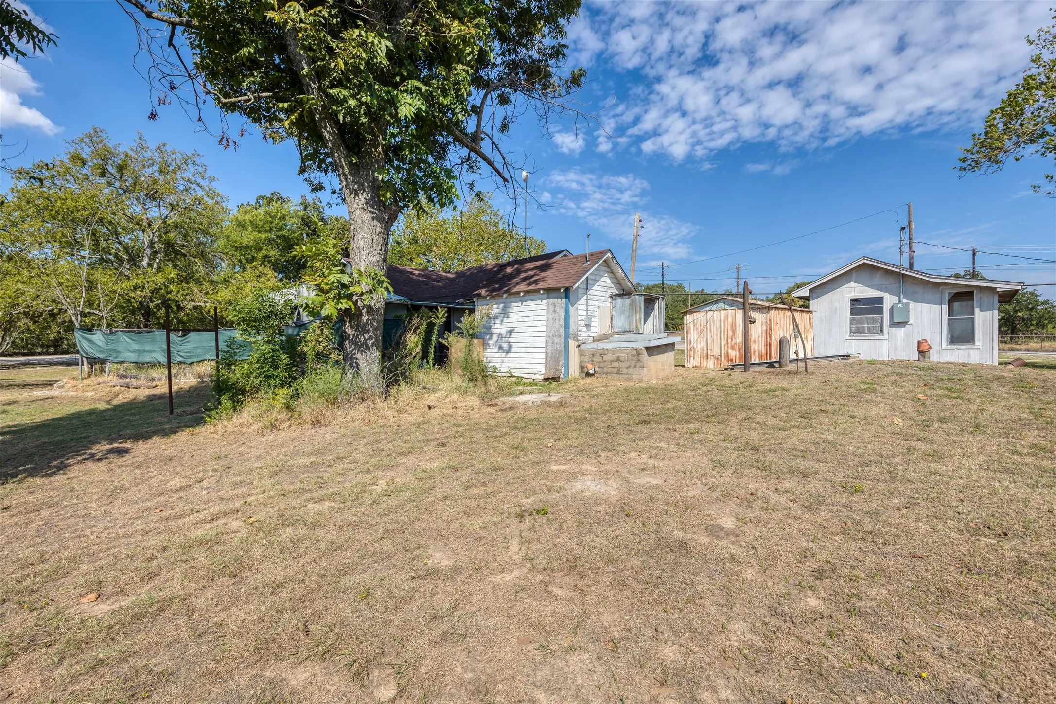 View of location of storm shelter, well house/storage building and back of house