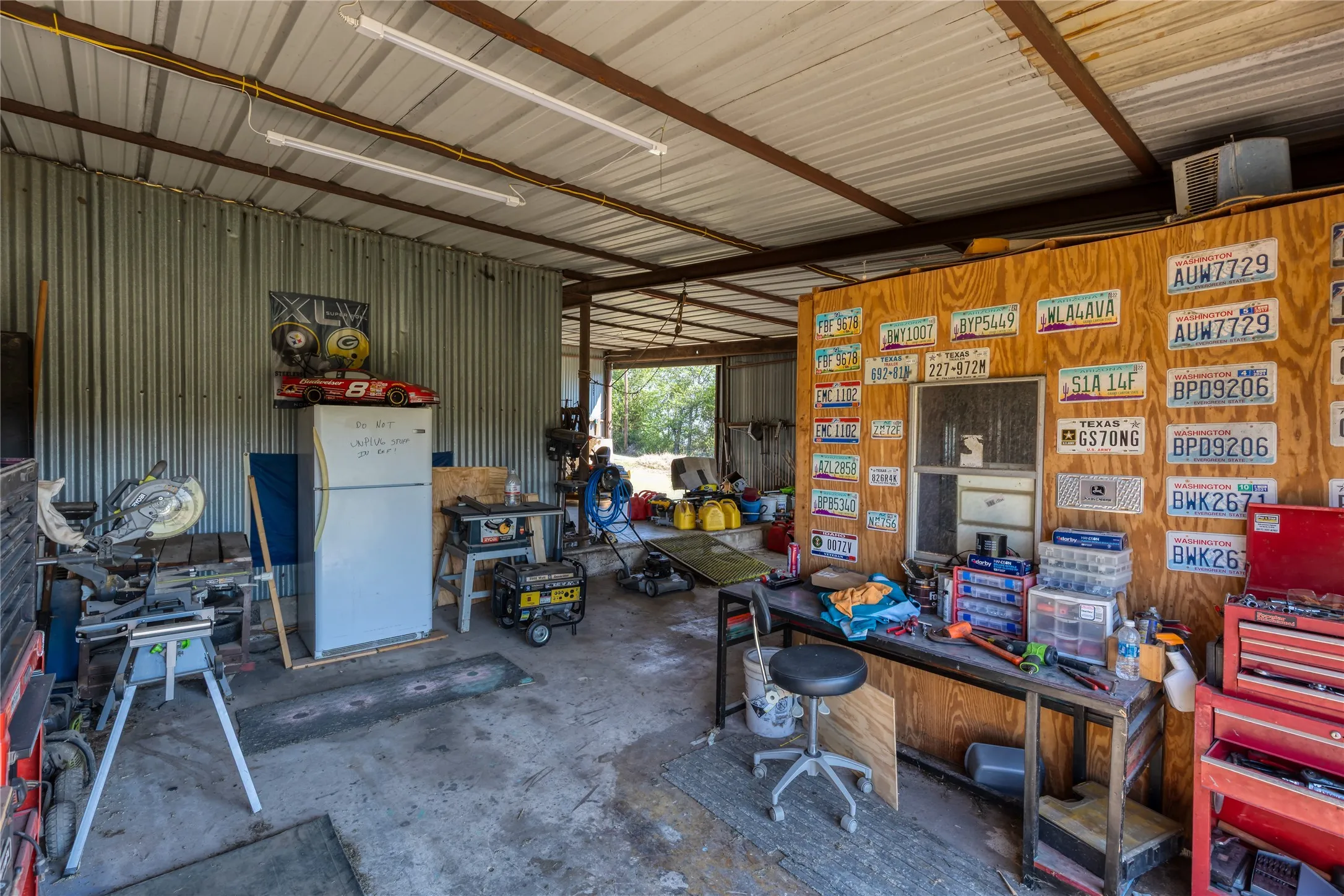 Garage with metal wall, freestanding refrigerator, and a workshop area