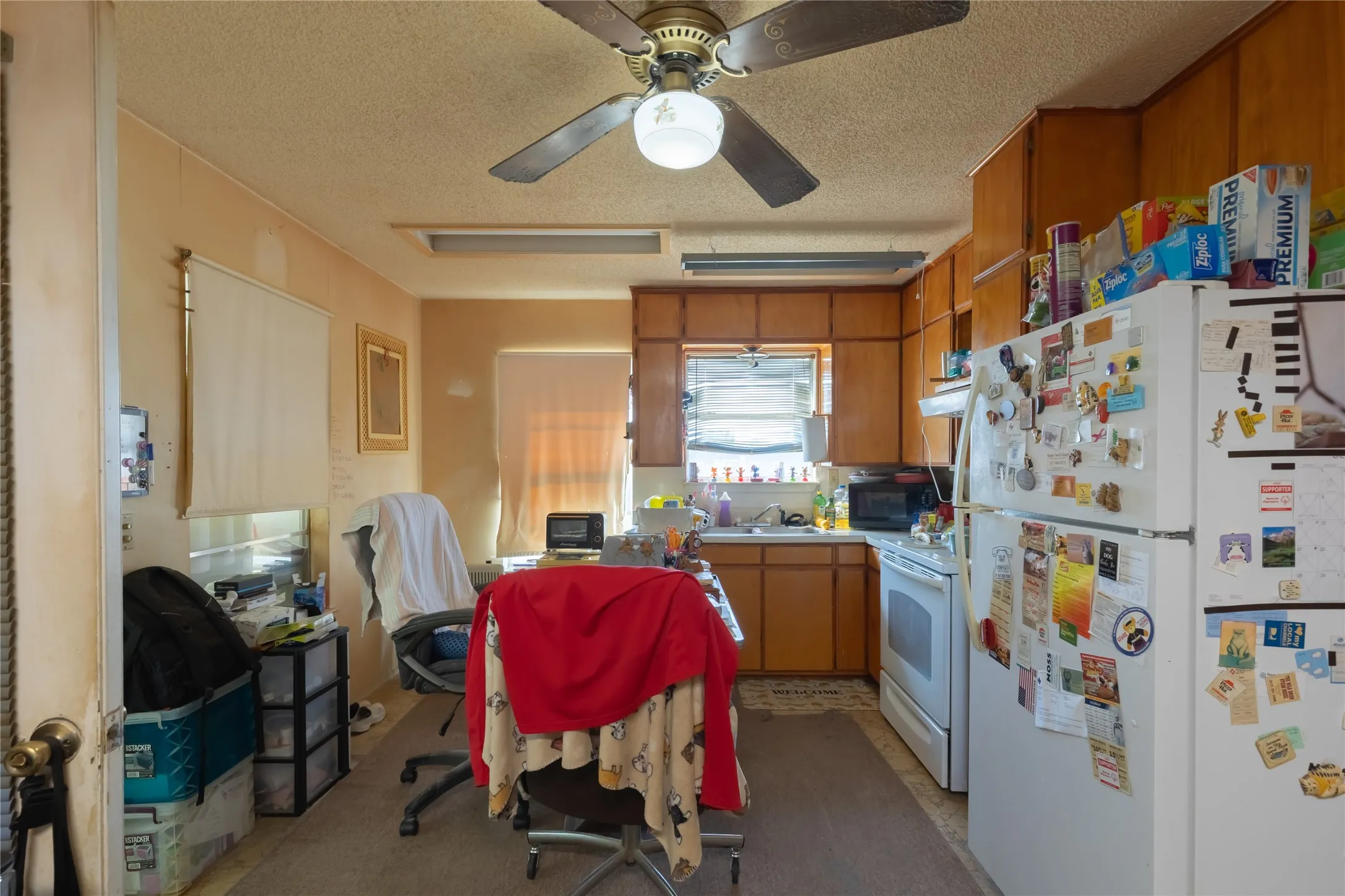 Kitchen with white appliances, brown cabinets, a textured ceiling, light countertops, and ceiling fan