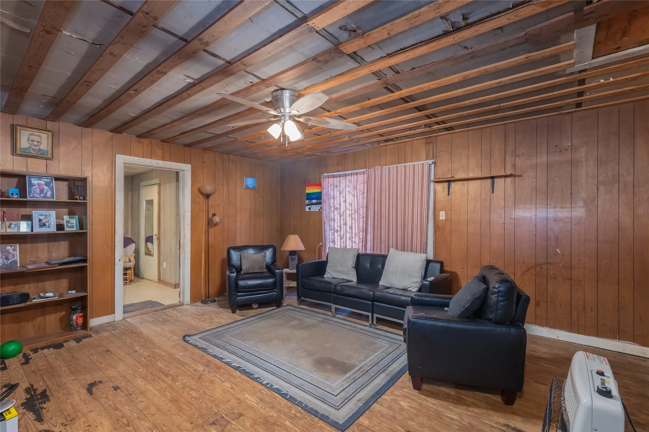 Living area featuring a ceiling fan, wood walls, and wood finished floors