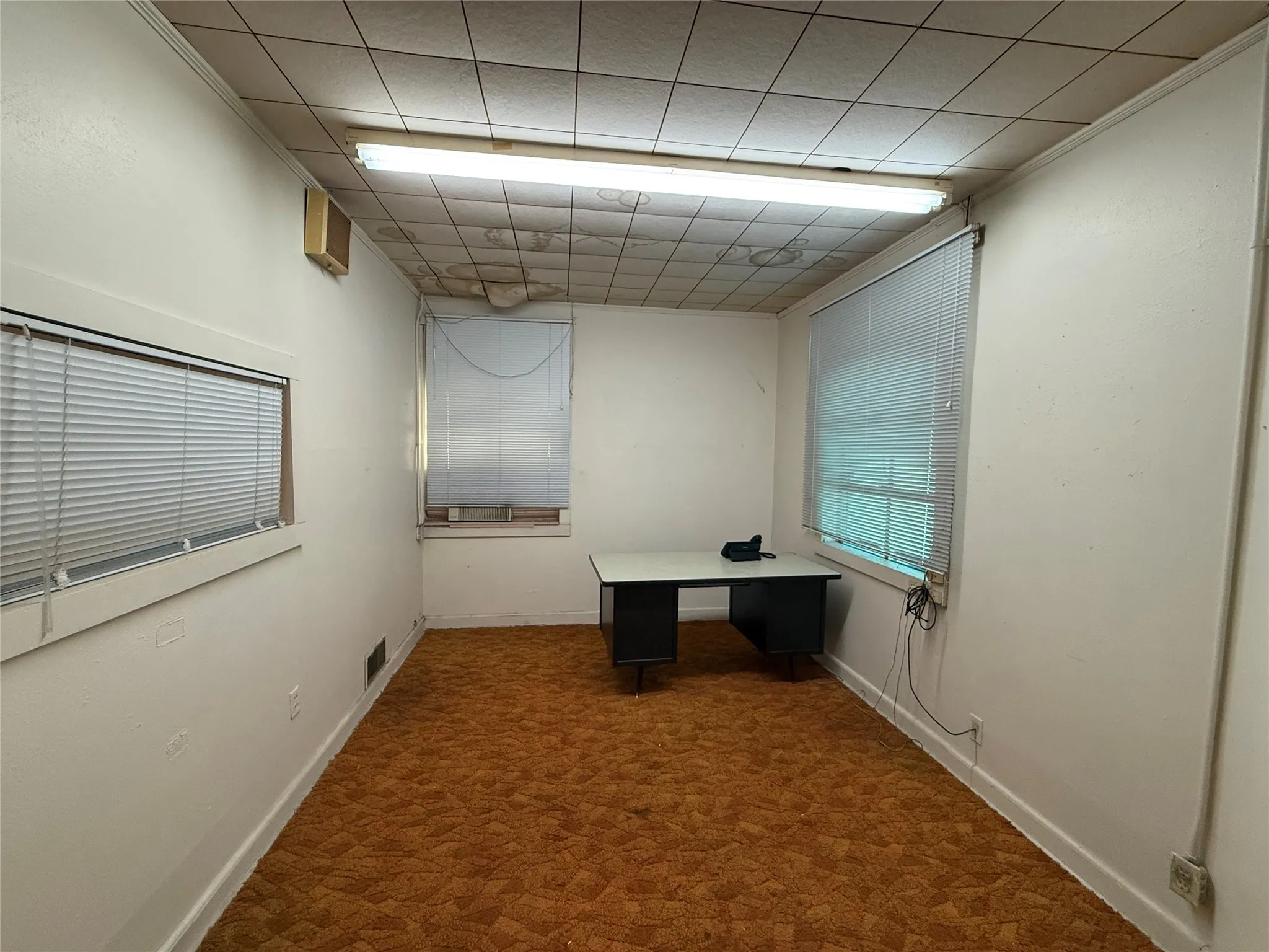 Unfurnished office with a drop ceiling and baseboards