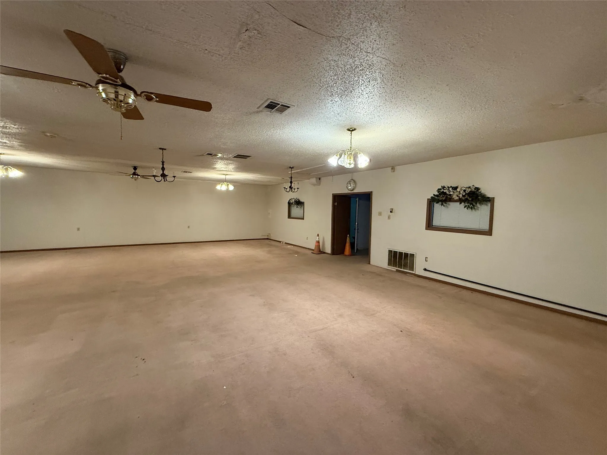 Empty room with a textured ceiling, concrete flooring, and ceiling fan