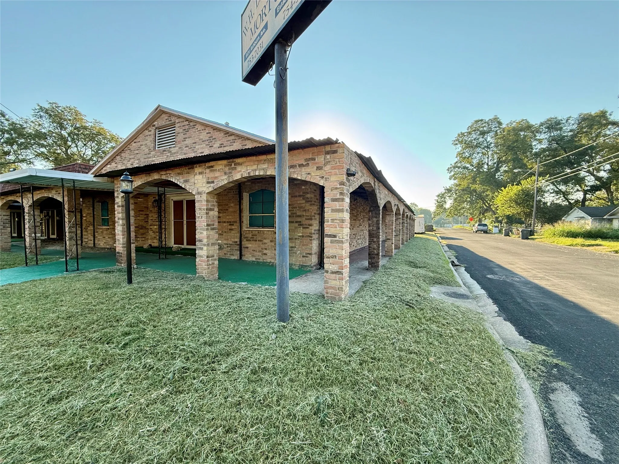 View of side of property with a patio area, a lawn, and brick siding