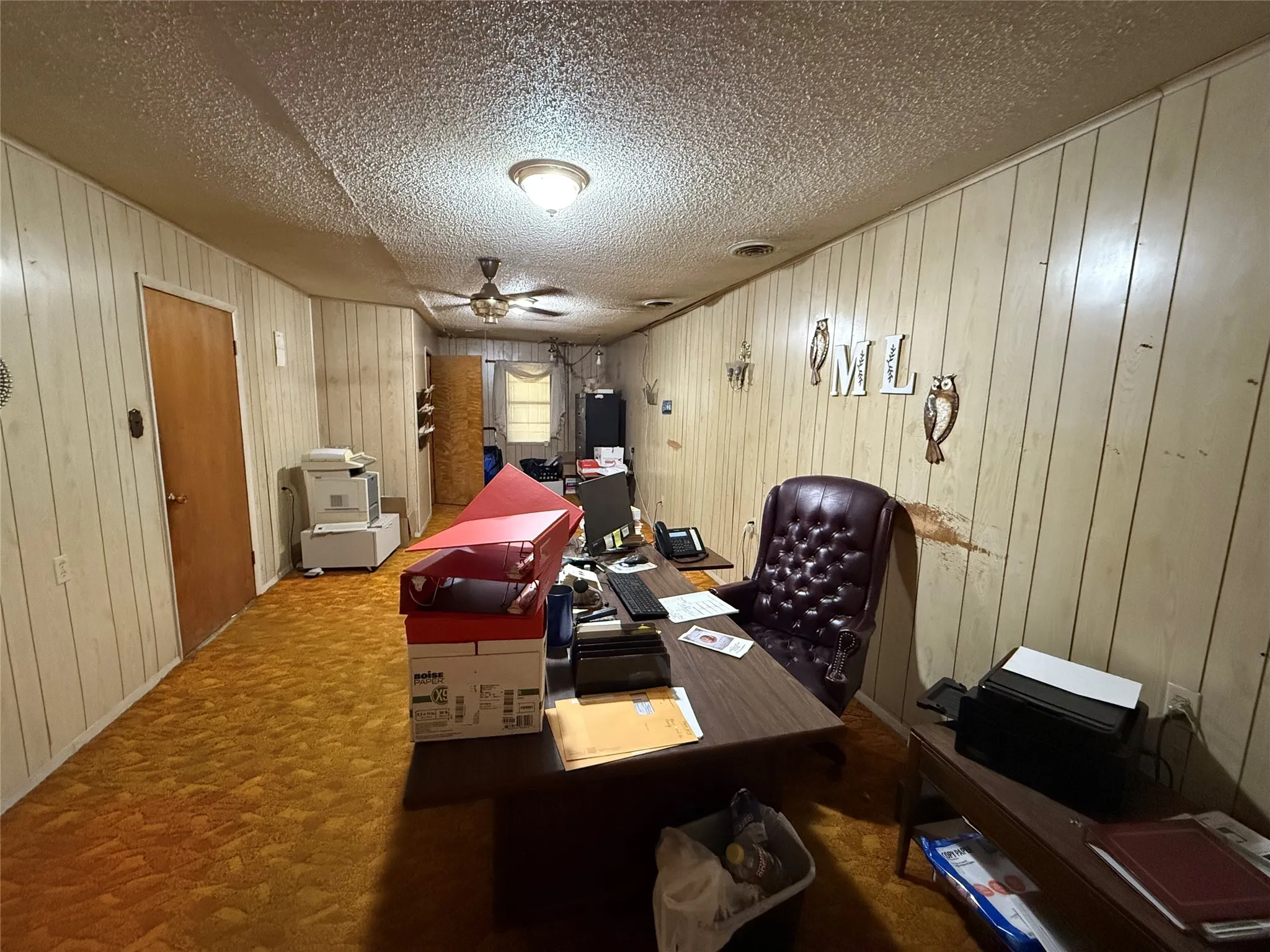 Office space featuring ceiling fan, a textured ceiling, and wooden walls