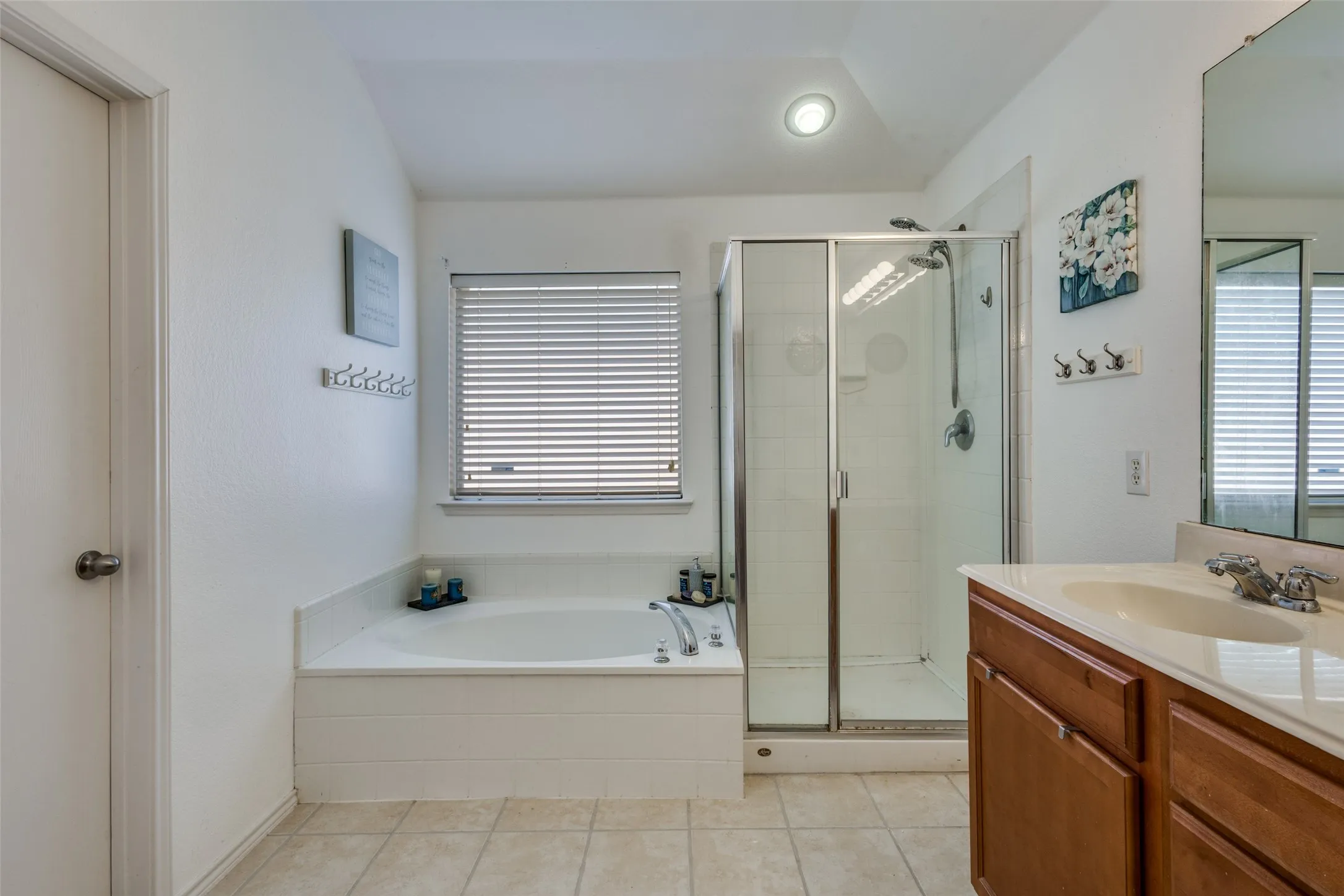 Full bath featuring a shower stall, vanity, a garden tub, light tile patterned flooring, and lofted ceiling