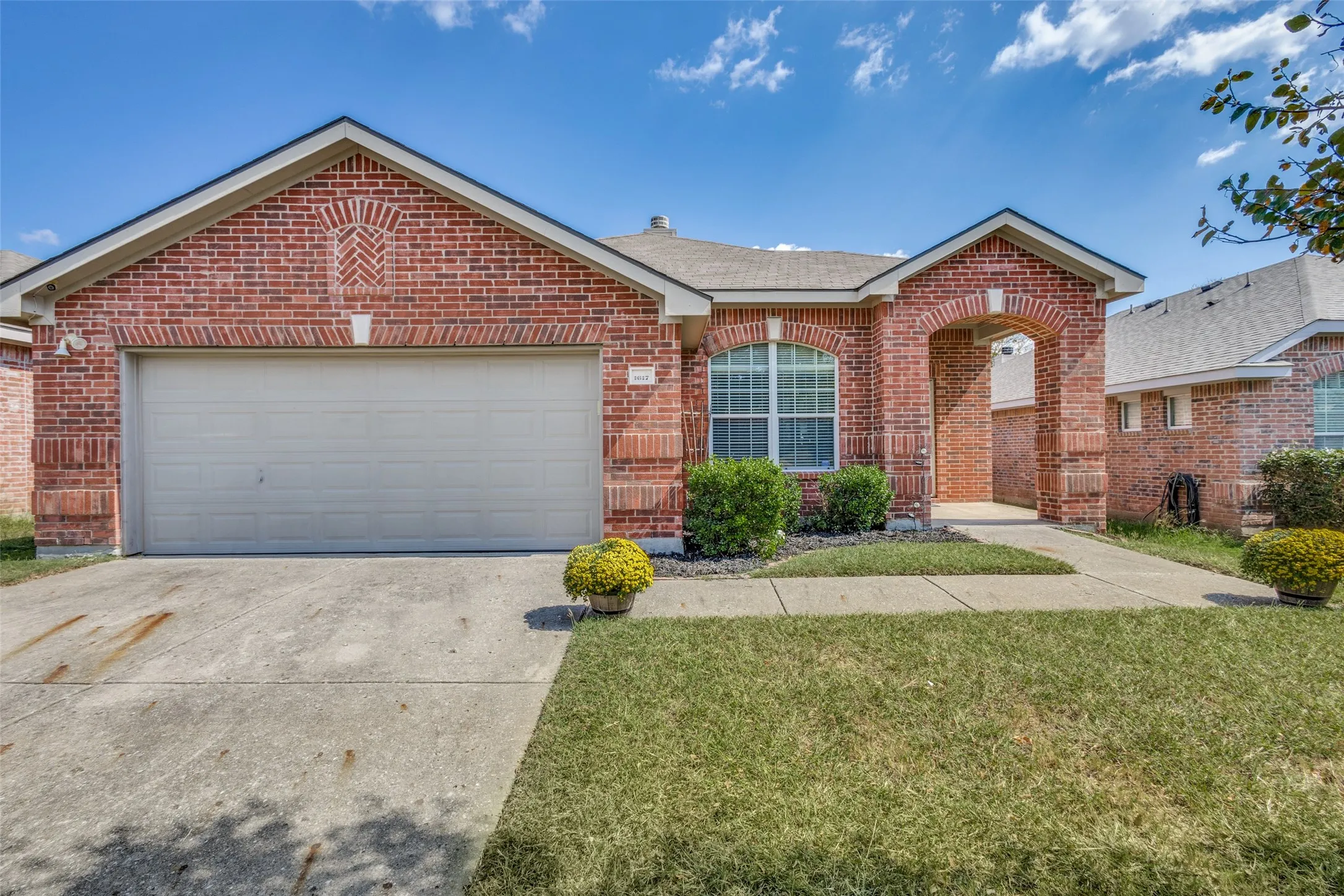 View of front of property featuring concrete driveway, a front lawn, brick siding, an attached garage, and a shingled roof