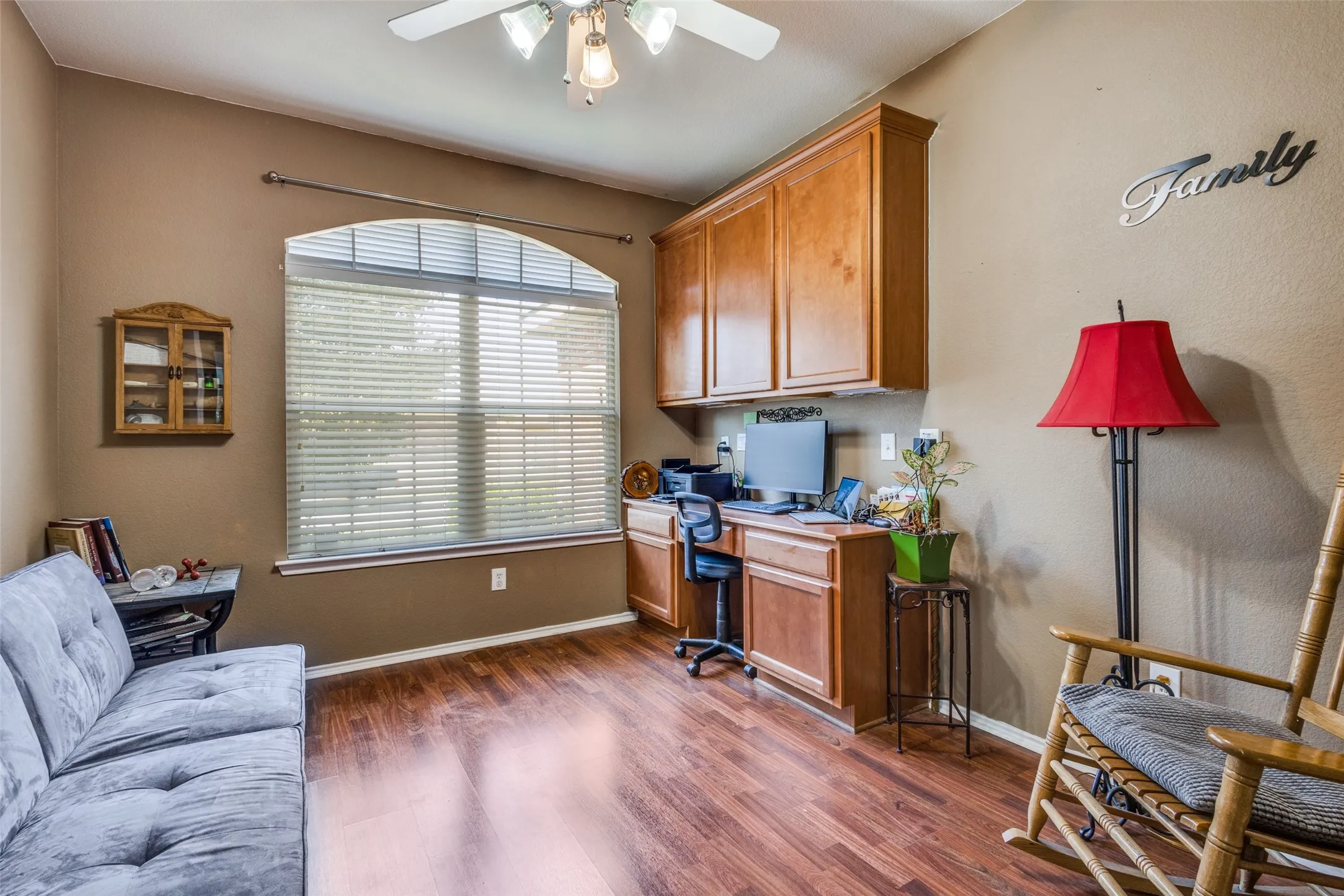 Home office with dark wood-type flooring and a ceiling fan