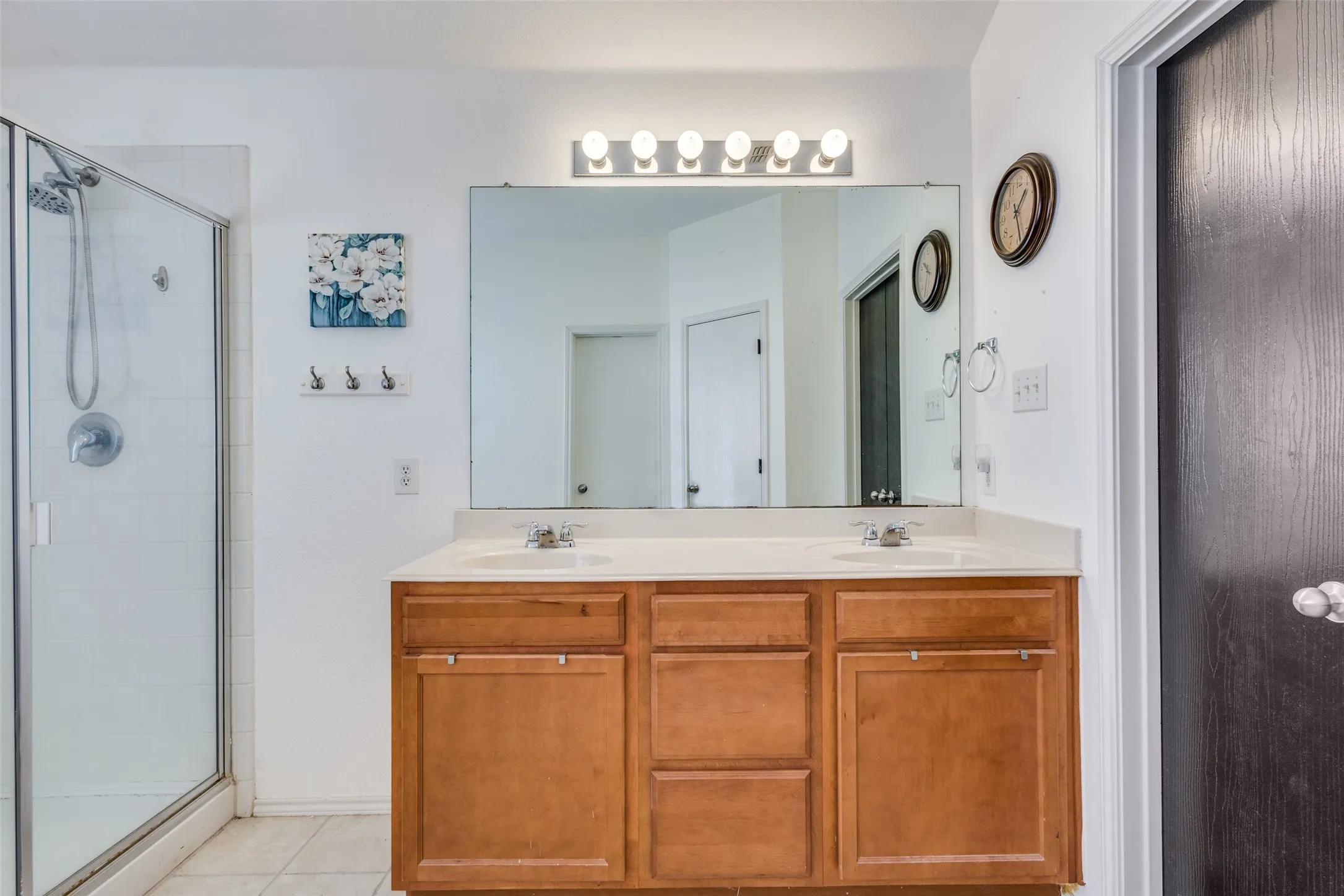 Full bath with a stall shower, double vanity, and light tile patterned floors