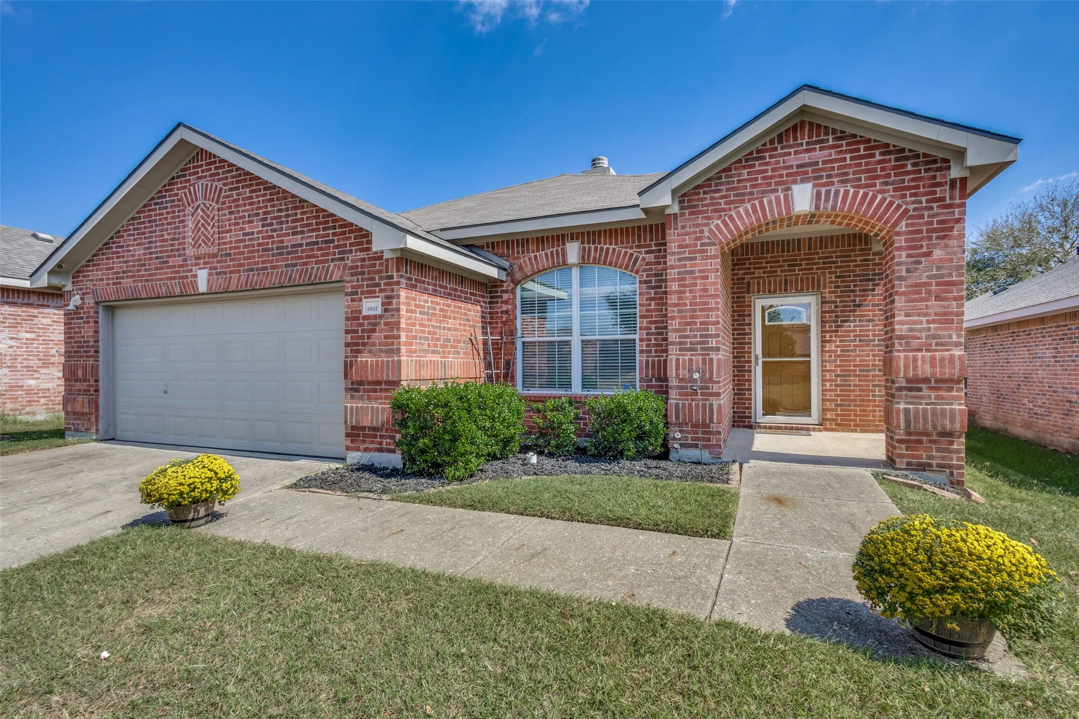View of front of property with brick siding, concrete driveway, a front lawn, and a garage