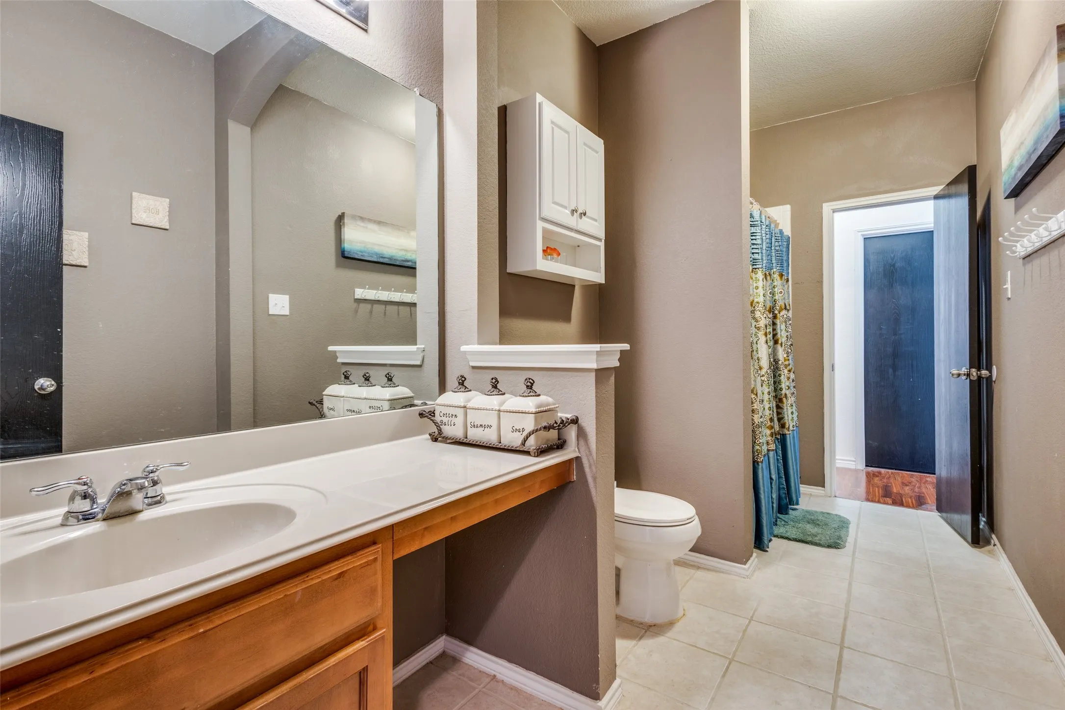Full bathroom featuring light tile patterned floors, vanity, and curtained shower