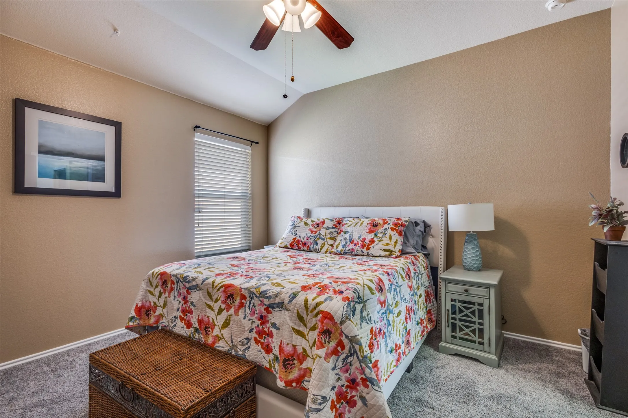 Bedroom featuring a textured wall, carpet flooring, lofted ceiling, and a ceiling fan