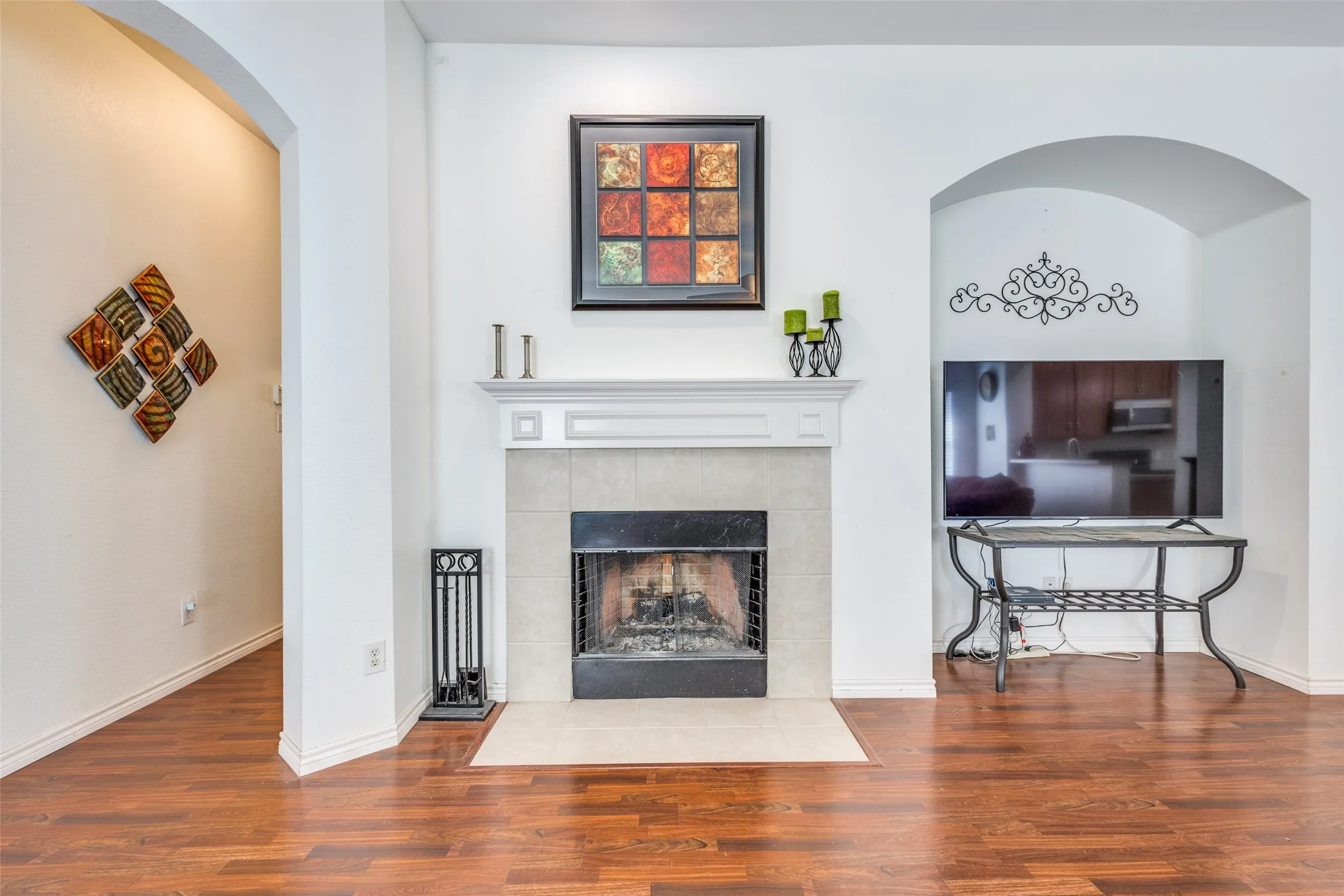 Living room with arched walkways, wood finished floors, and a fireplace