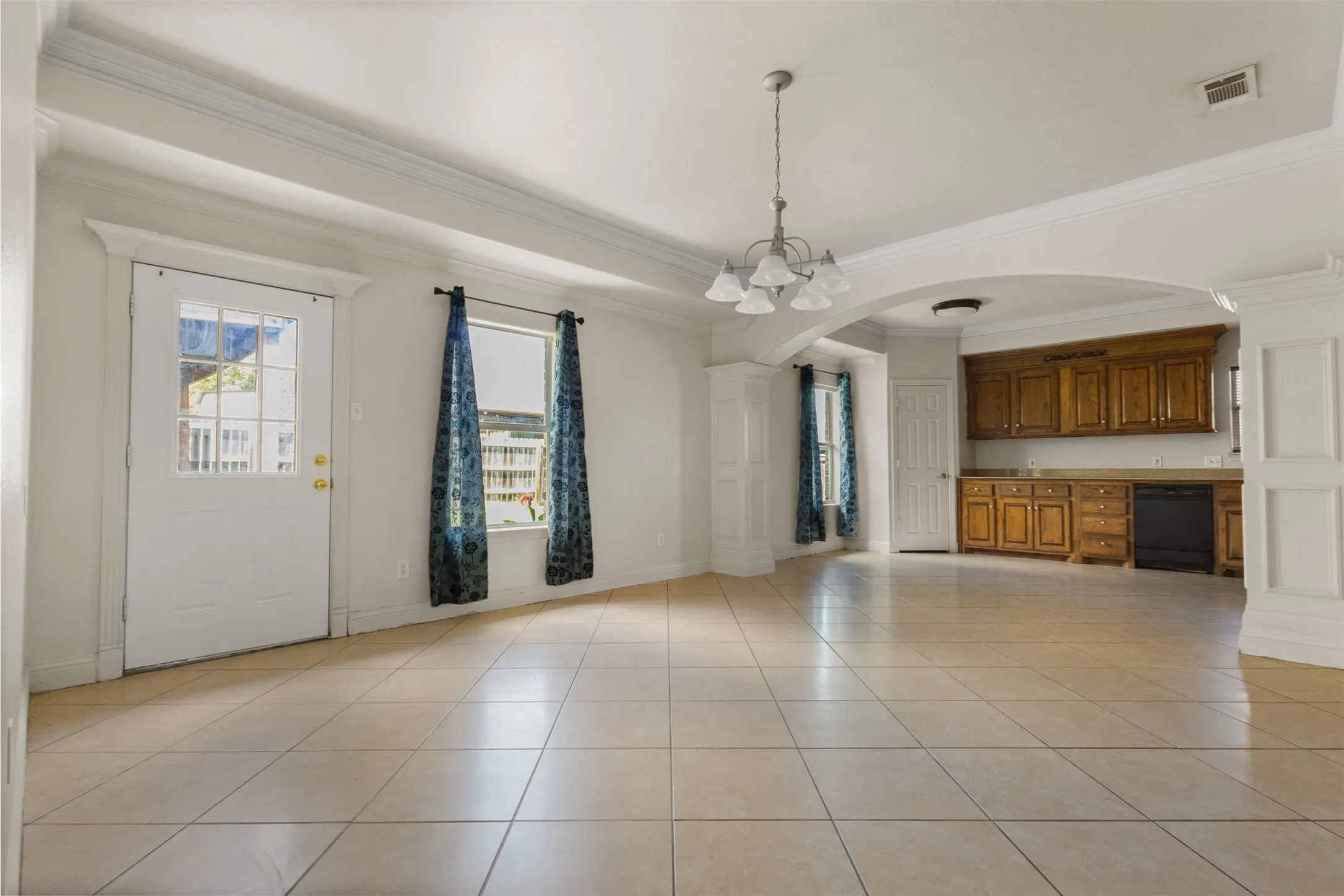 Unfurnished dining area with arched walkways, crown molding, light tile patterned floors, and a chandelier