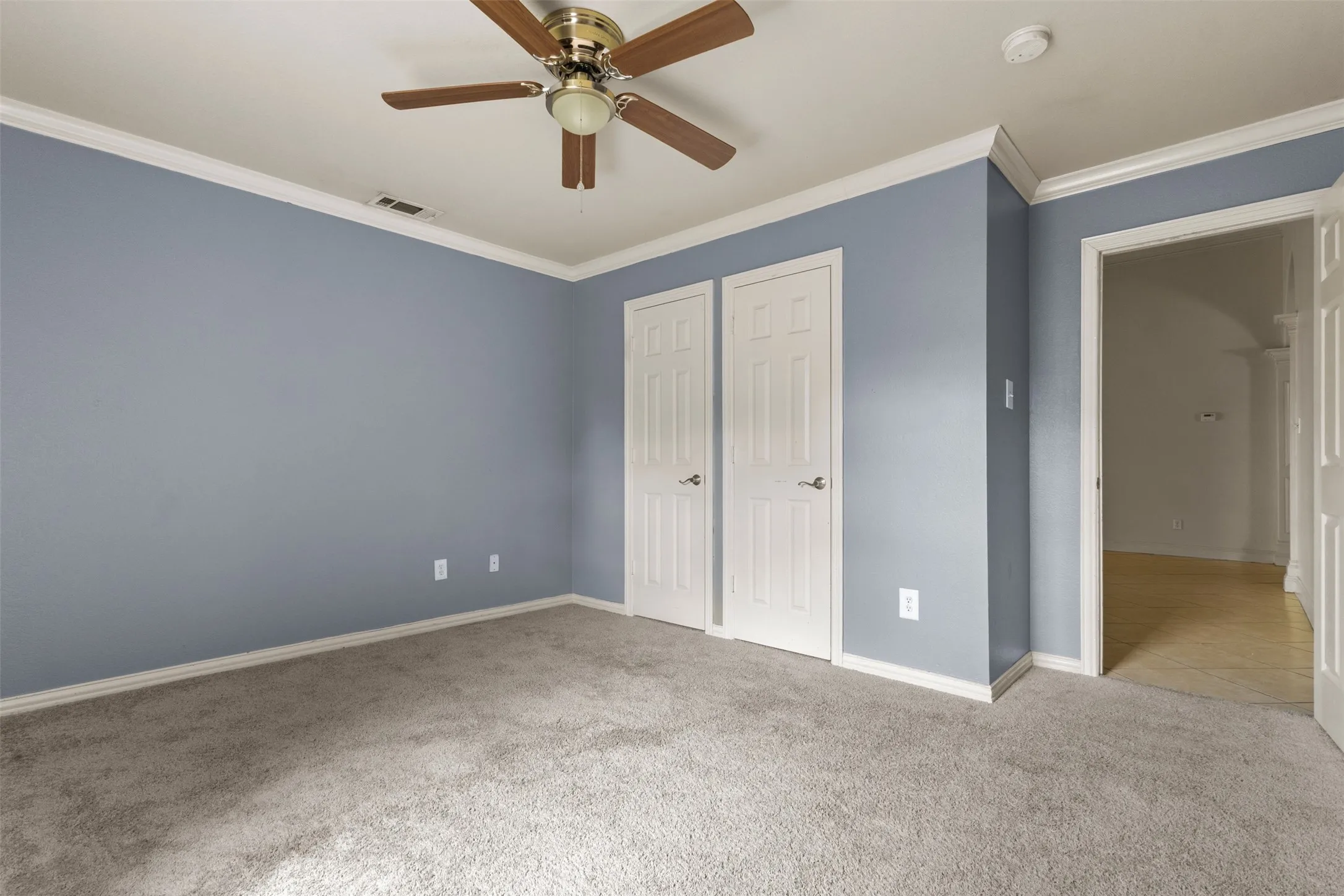 Unfurnished bedroom featuring crown molding, light colored carpet, ceiling fan, and a closet