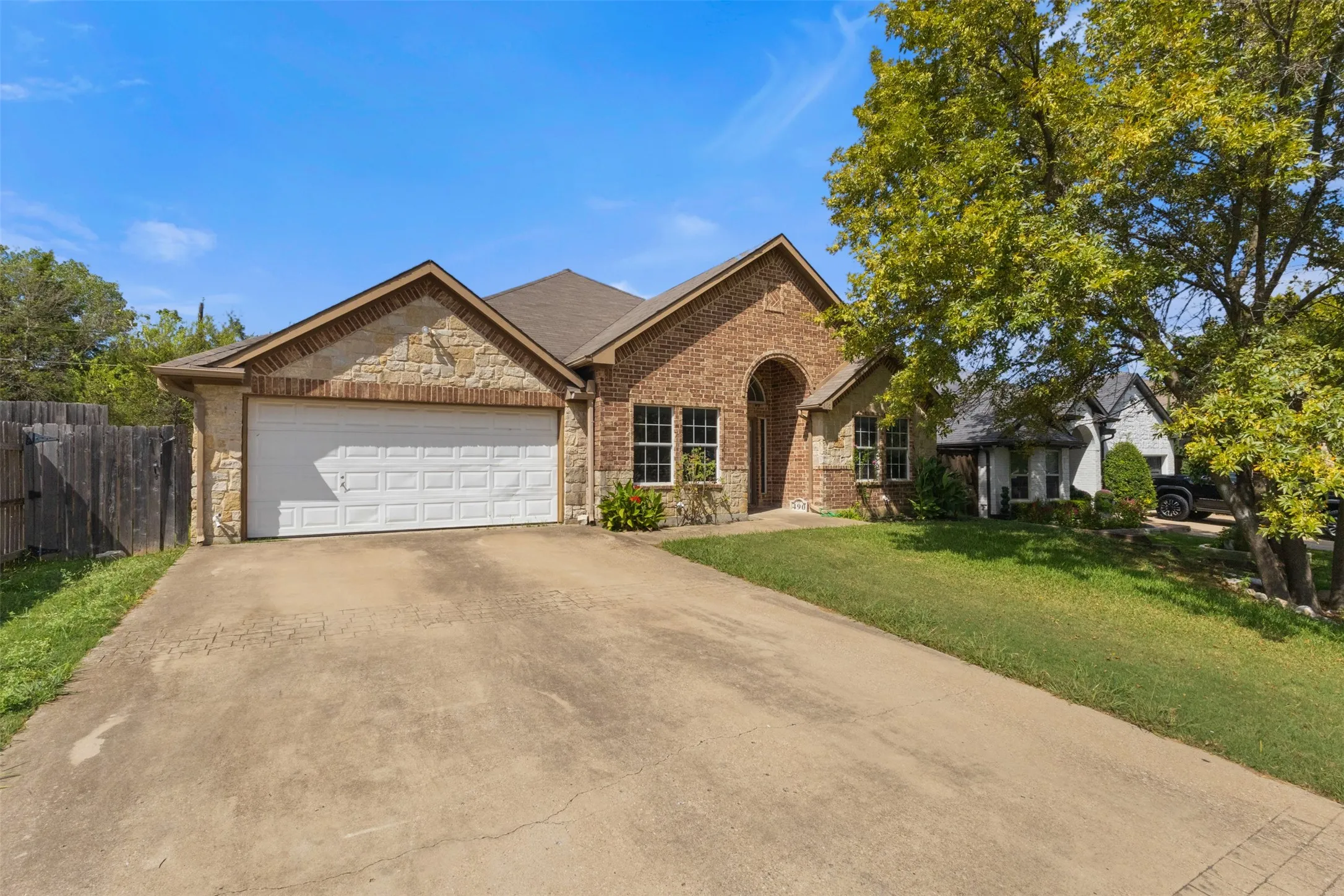 View of front of property featuring driveway, stone siding, brick siding, and a garage