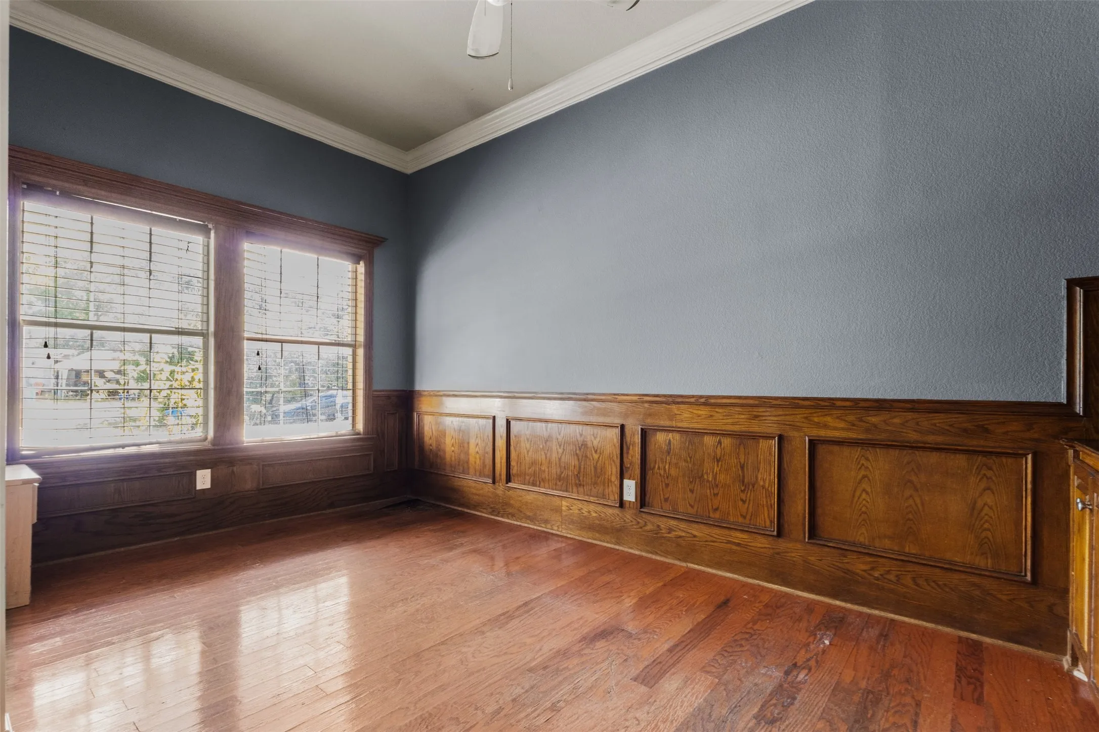 Unfurnished room with crown molding, hardwood / wood-style floors, a wainscoted wall, and ceiling fan