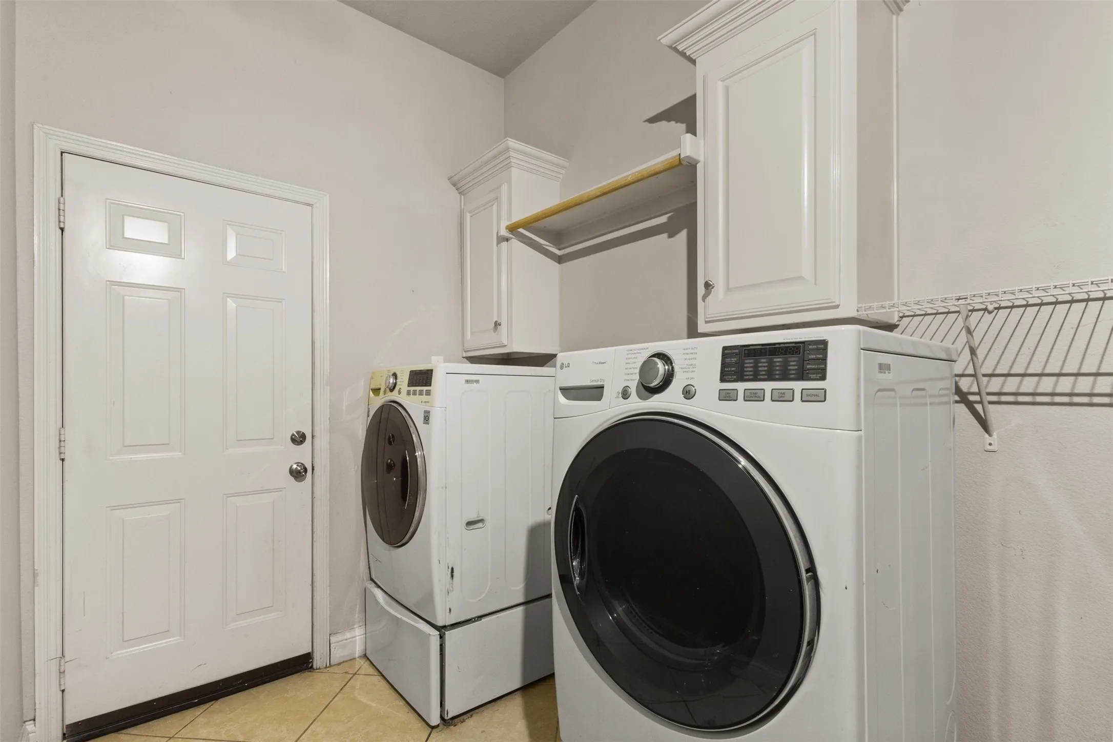 Washroom featuring light tile patterned floors, cabinet space, and washer and clothes dryer