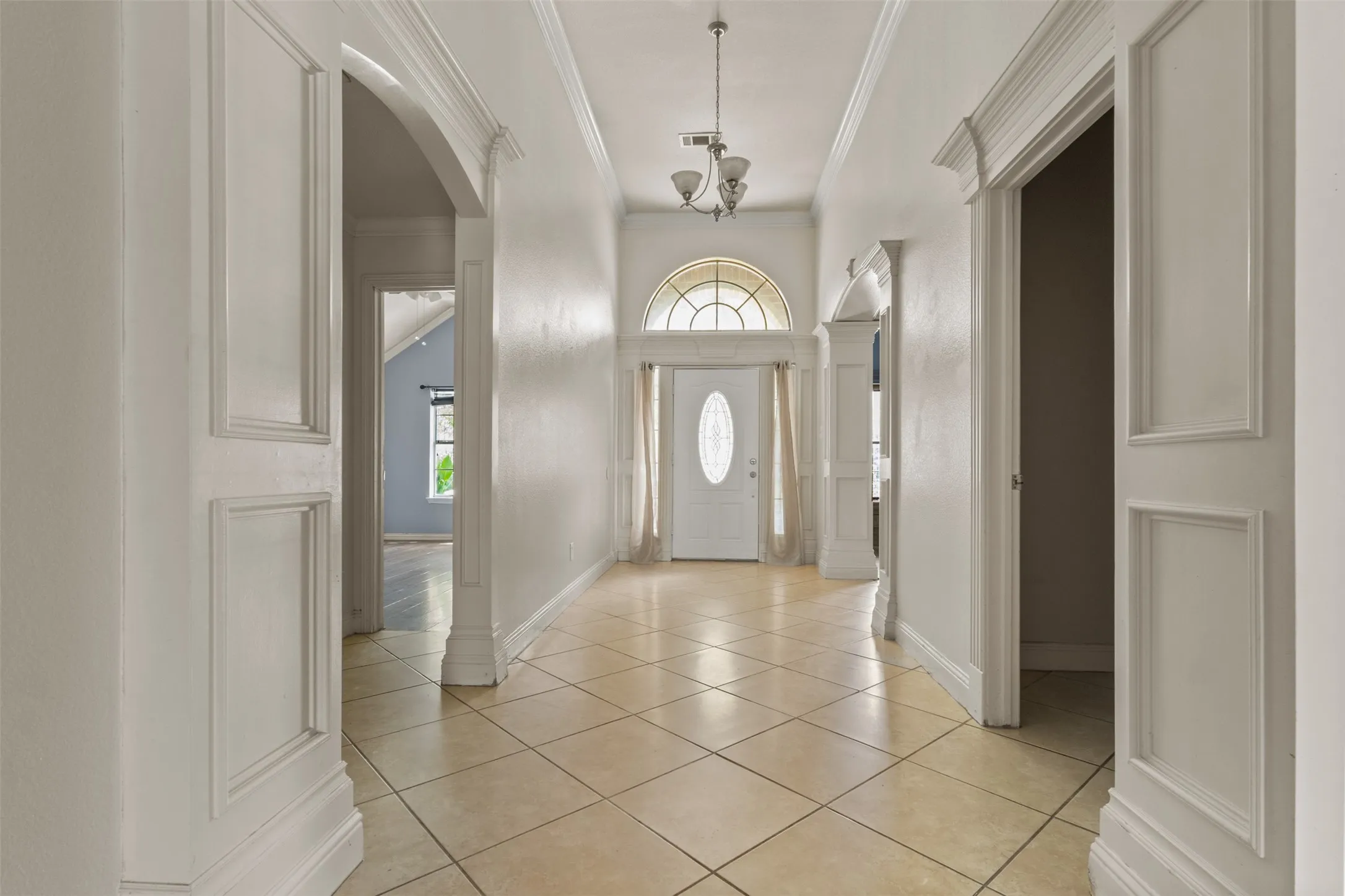 Foyer featuring light tile patterned floors, plenty of natural light, arched walkways, and ornamental molding