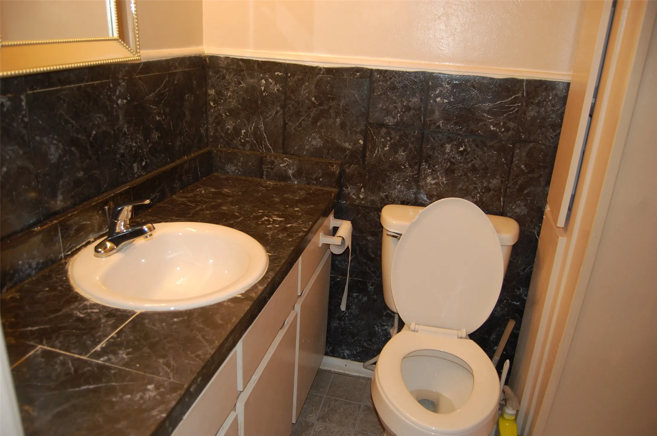 Master Bathroom with vanity, dark tile patterned flooring, tile walls, and wainscoting