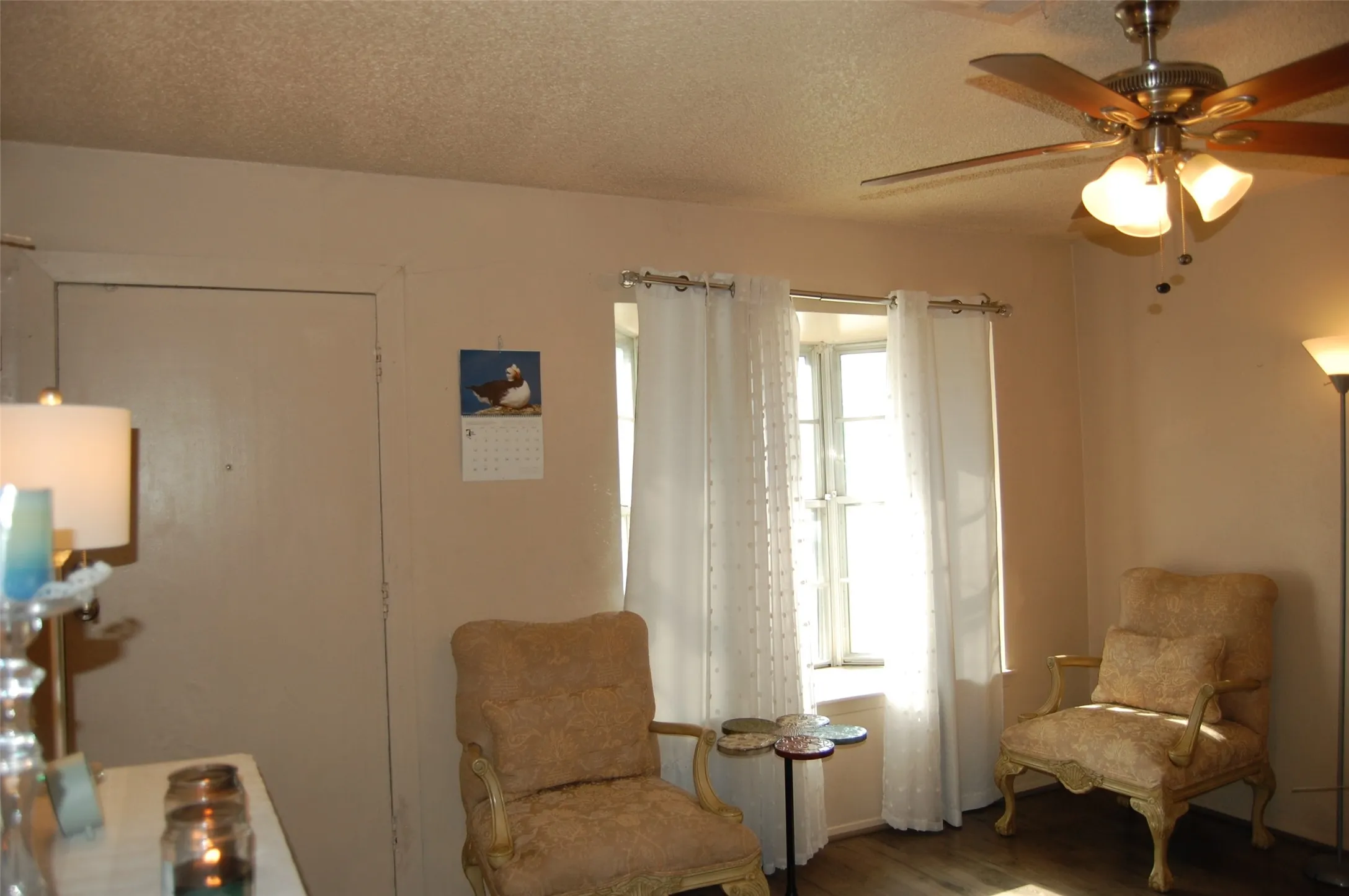 Living area with a textured ceiling, ceiling fan, and wood finished floors
