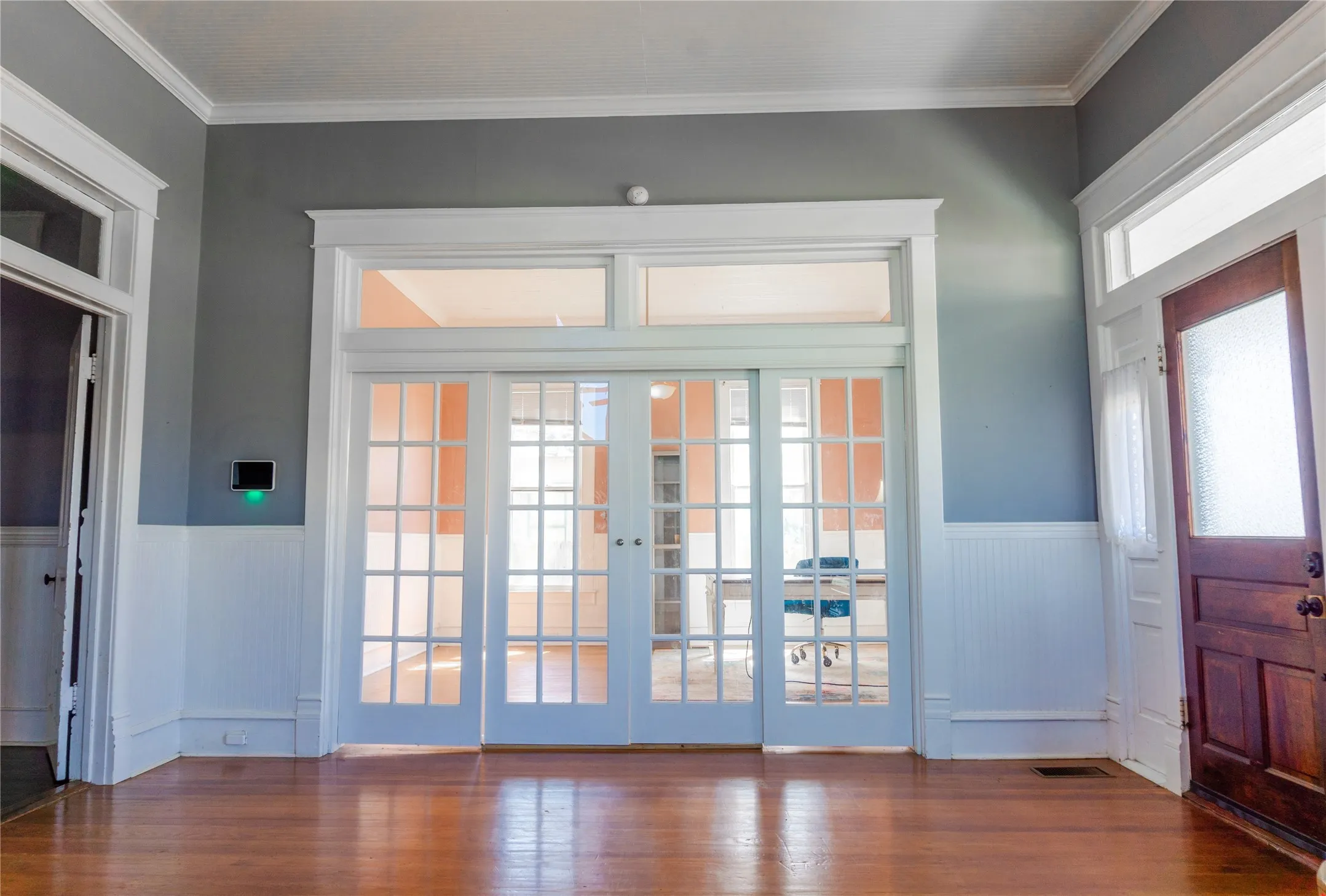 Doorway with wainscoting, french doors, crown molding, and wood finished floors