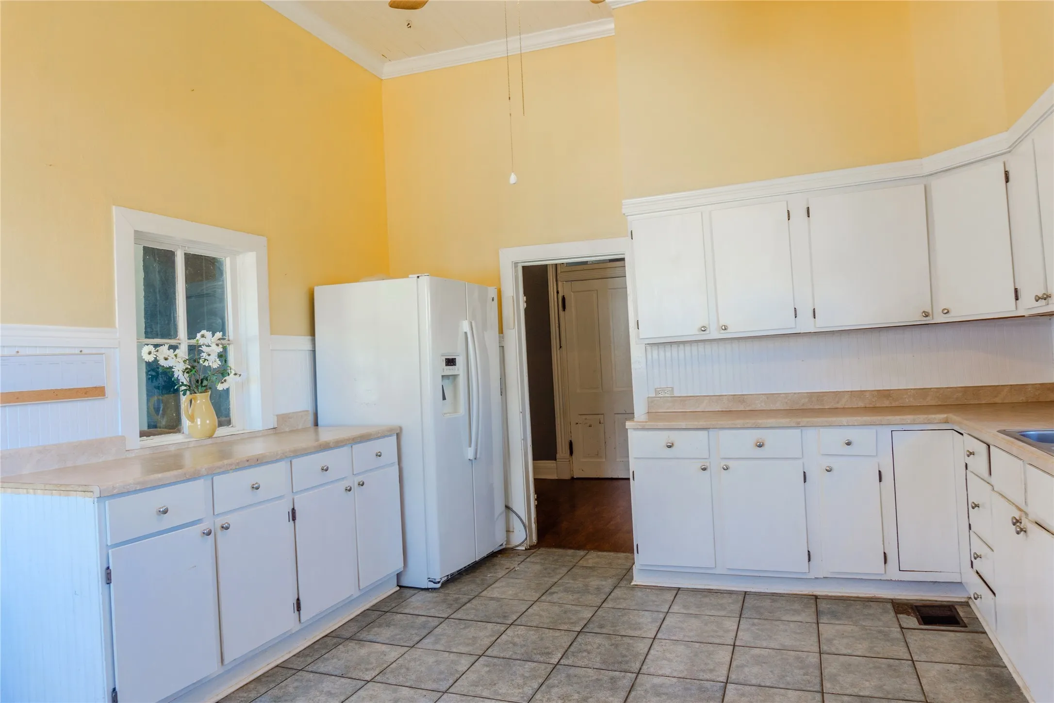 Kitchen with white cabinetry, light countertops, white refrigerator with ice dispenser, a high ceiling, and light tile patterned floors