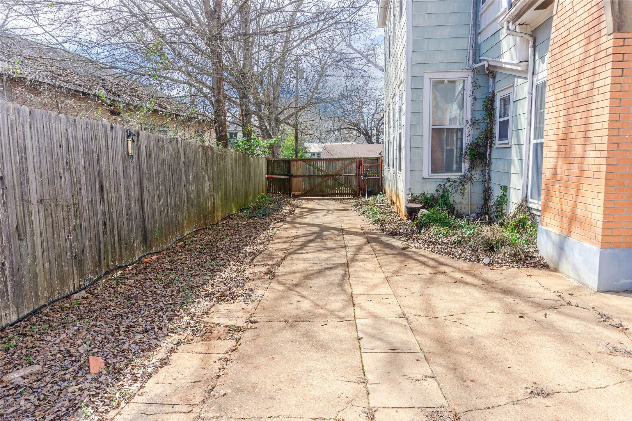 View of patio with a gate and concrete driveway
