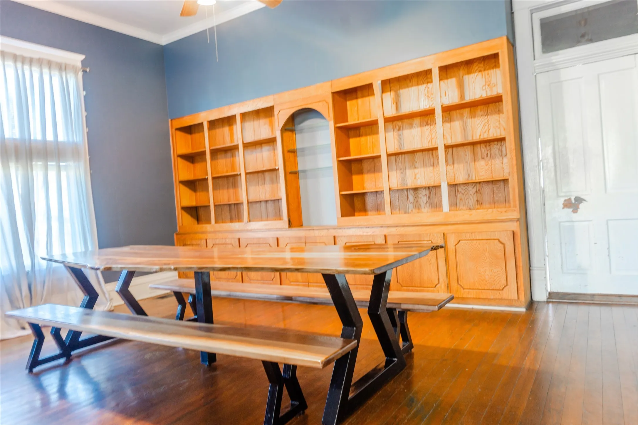 Unfurnished dining area featuring dark wood-type flooring, ceiling fan, and ornamental molding