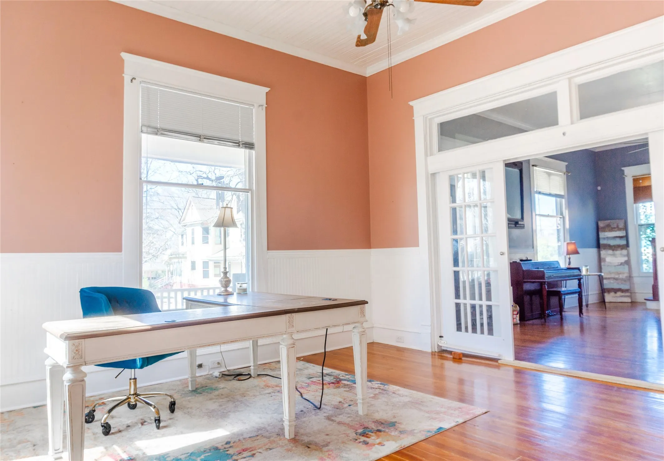 Office with wainscoting, light wood-type flooring, crown molding, and a ceiling fan