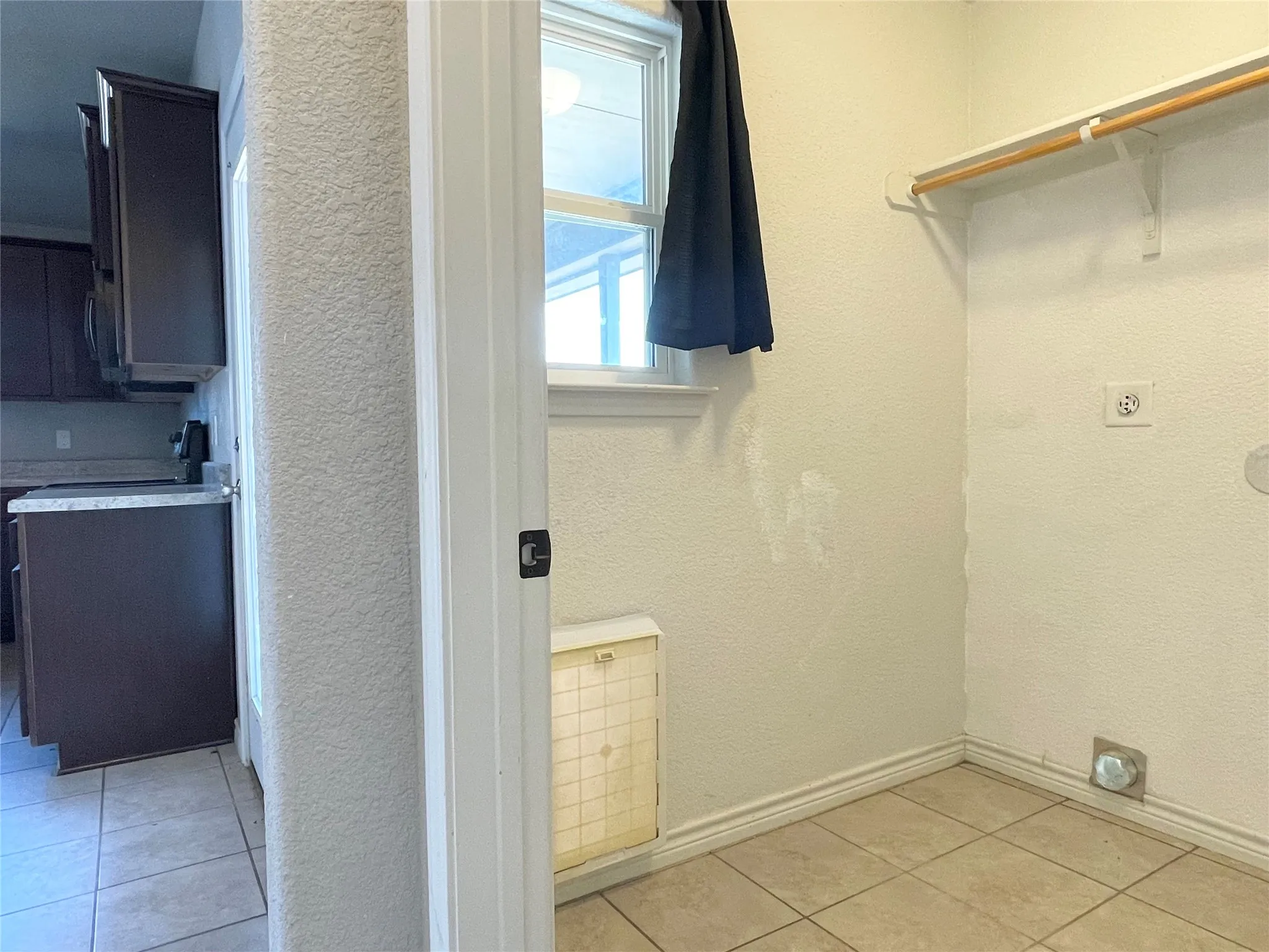 Laundry area featuring doggy-door, light tile floors, and hookup for an electric dryer