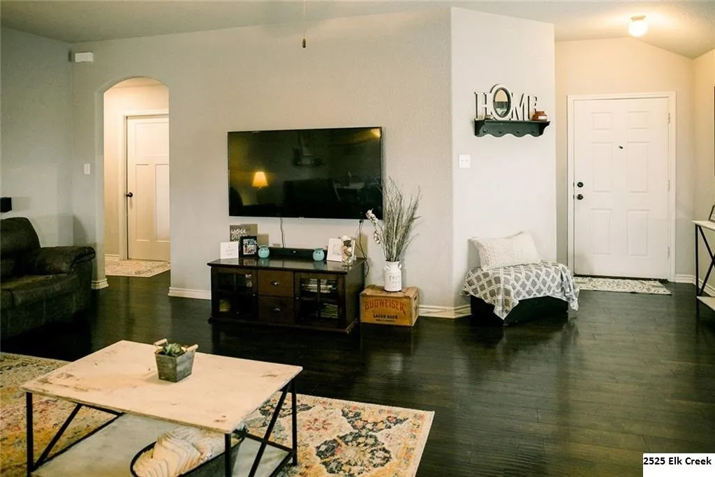 Living room featuring dark wood-type flooring, and arched walkways