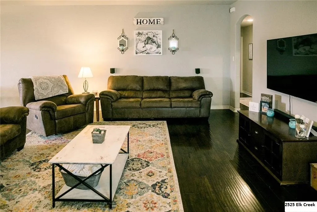 Living area featuring dark wood-style floors and arched walkways