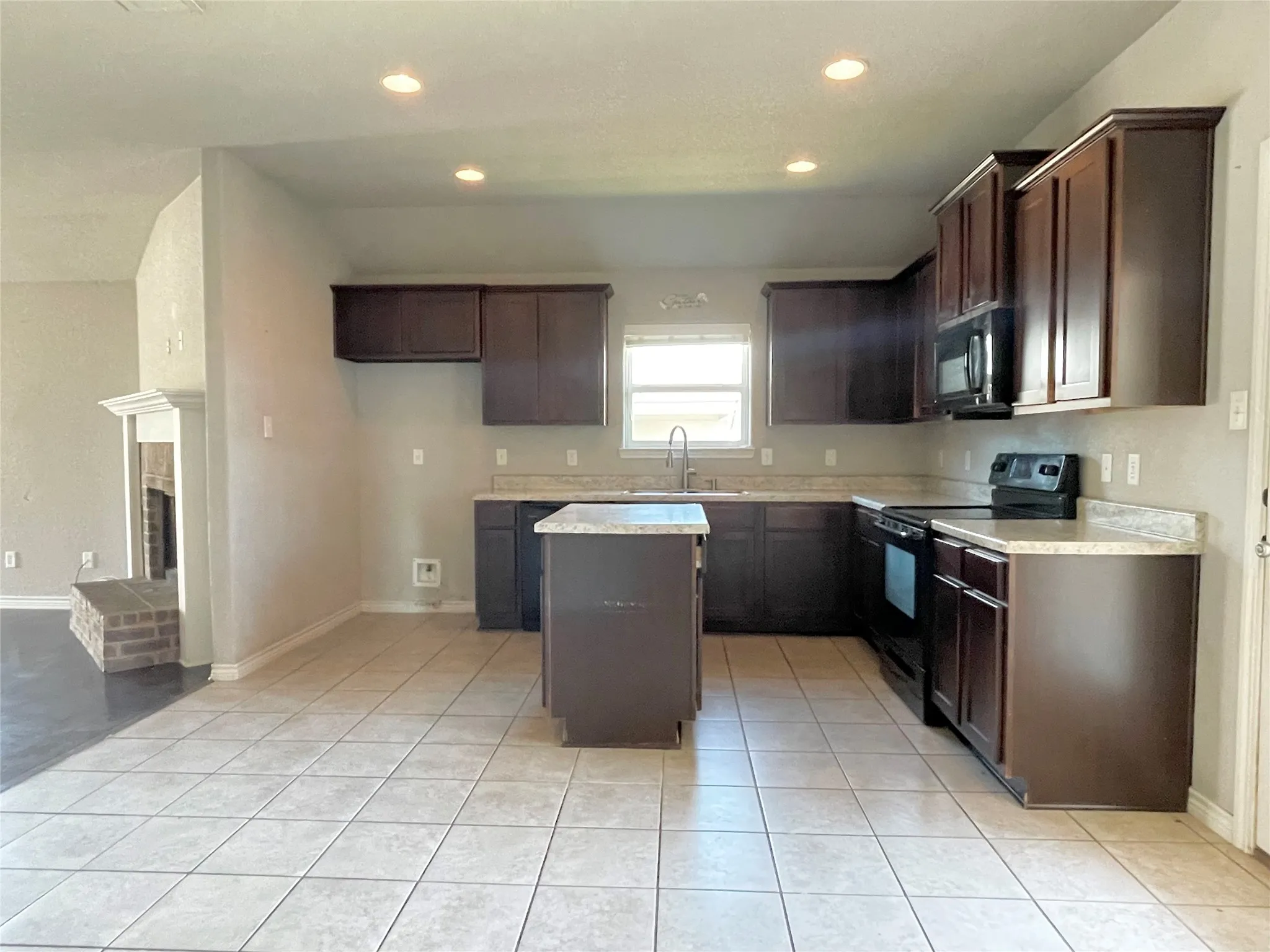 Kitchen featuring black appliances, dark brown cabinetry, a center island, light countertops, and recessed lighting