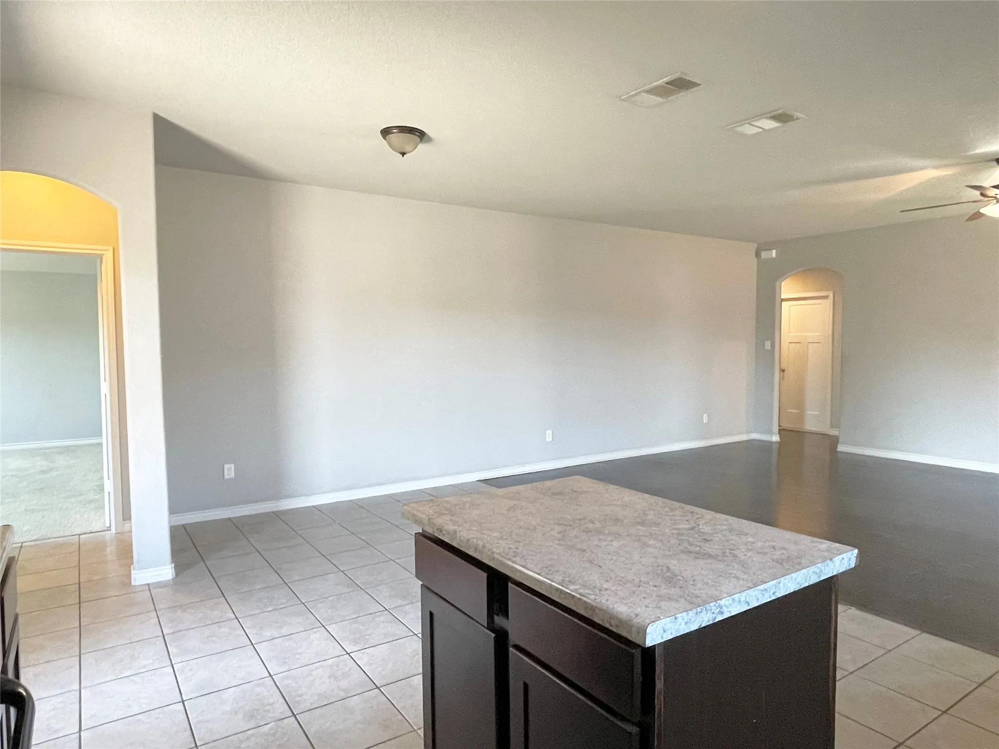 Kitchen with arched walkways, open floor plan, light tile patterned floors, and light countertops