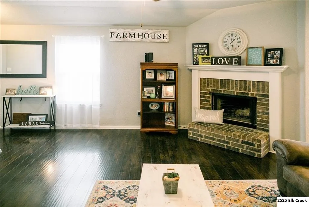 Living room featuring a brick fireplace and dark wood-style flooring