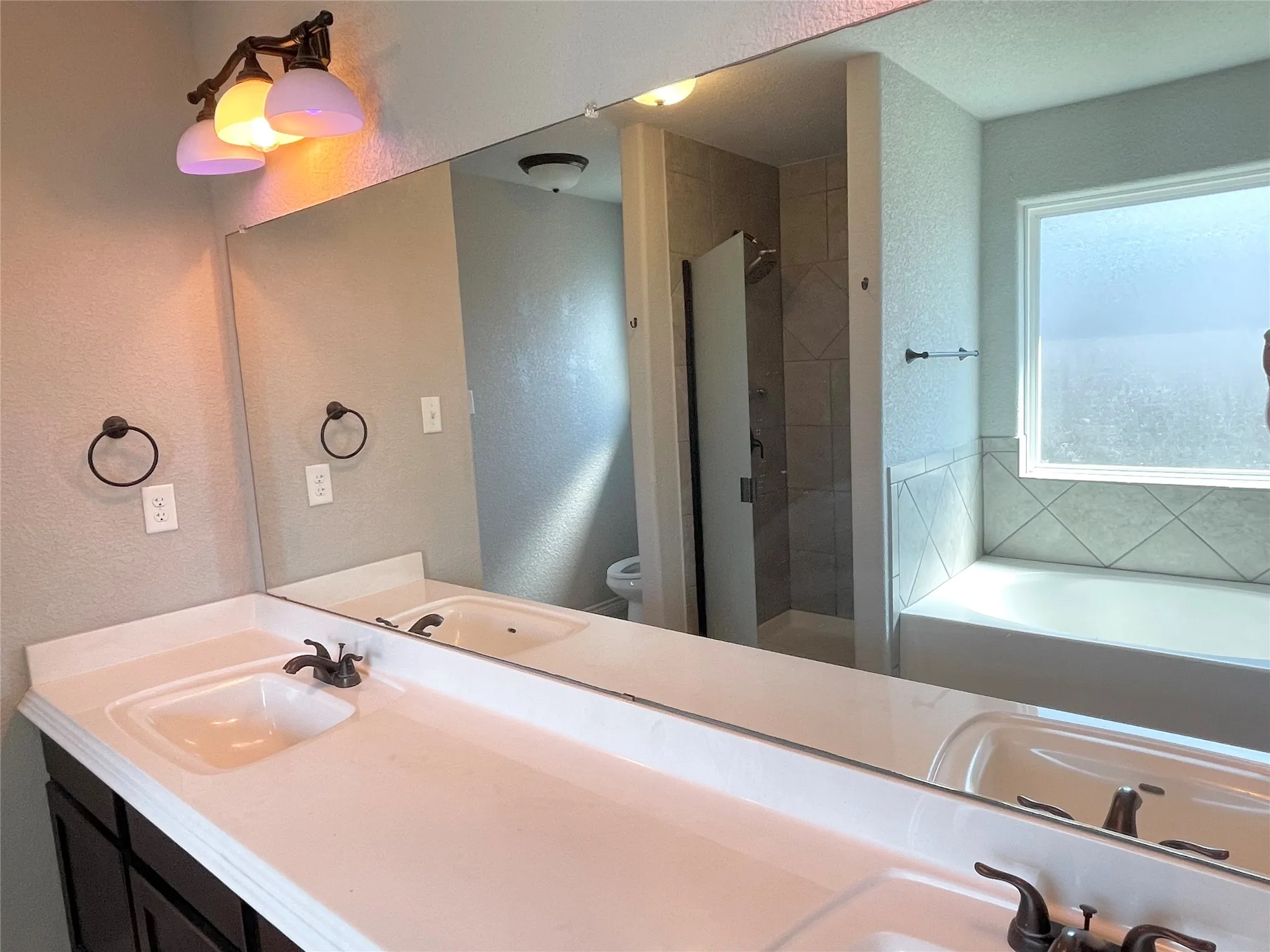 Primary ensuite bathroom featuring a bath, double vanity, and a shower stall