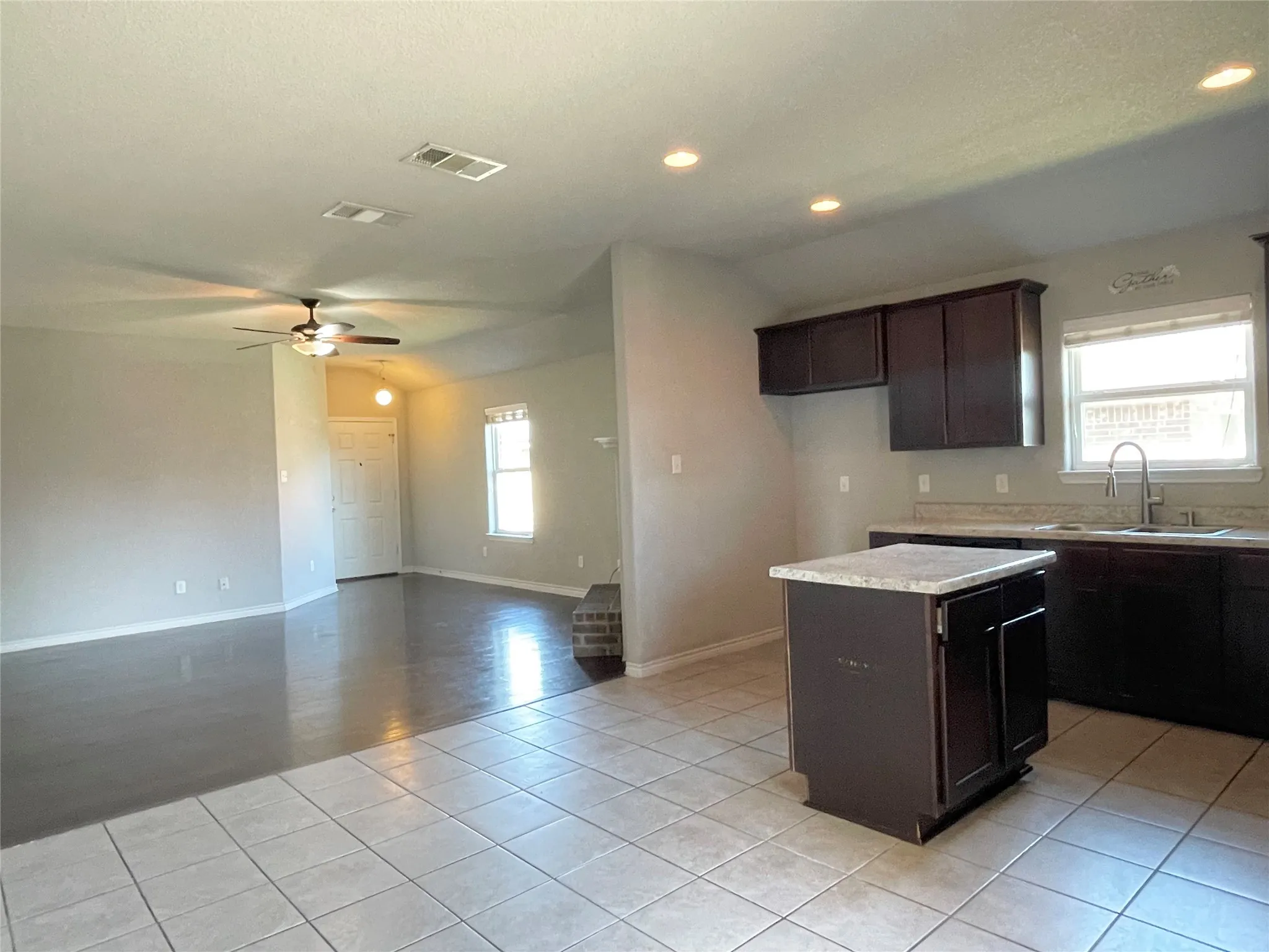 Kitchen featuring dark brown cabinetry, a kitchen island, light tile patterned flooring, recessed lighting, and a ceiling fan